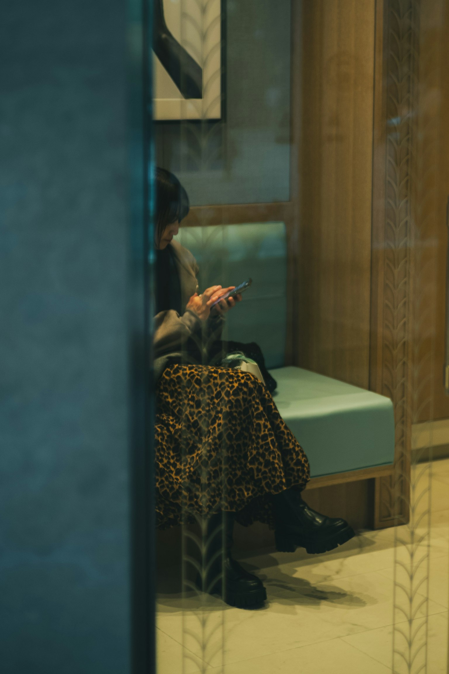 A woman in a leopard print skirt sitting on a sofa using a smartphone