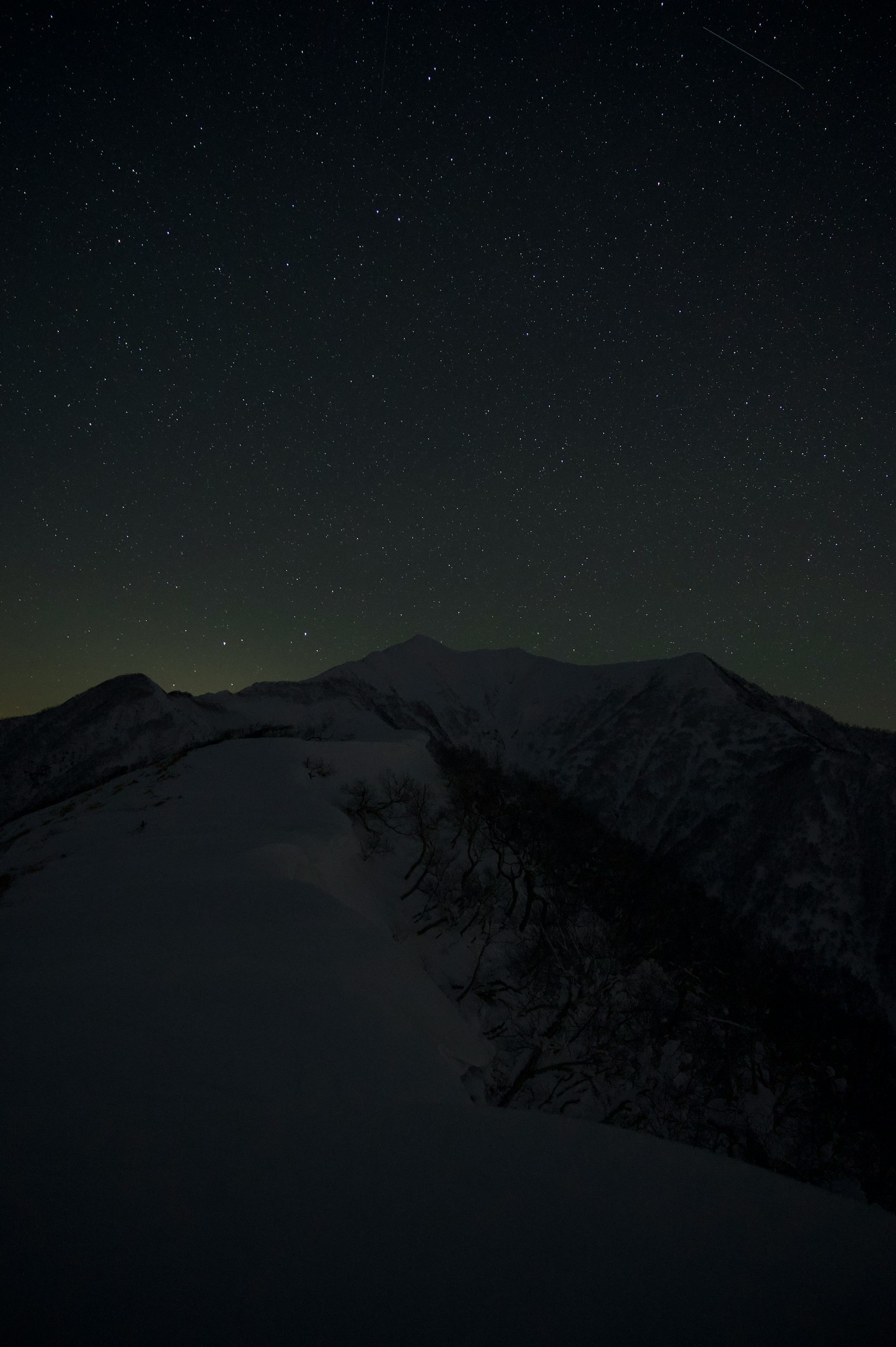Cima di montagna coperta di neve con cielo stellato