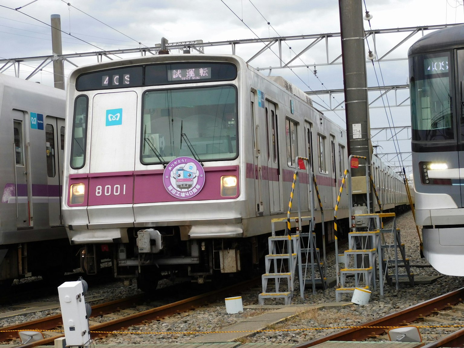 Sebuah kereta yang diparkir di rel dengan model 8001 dan kereta yang berdekatan