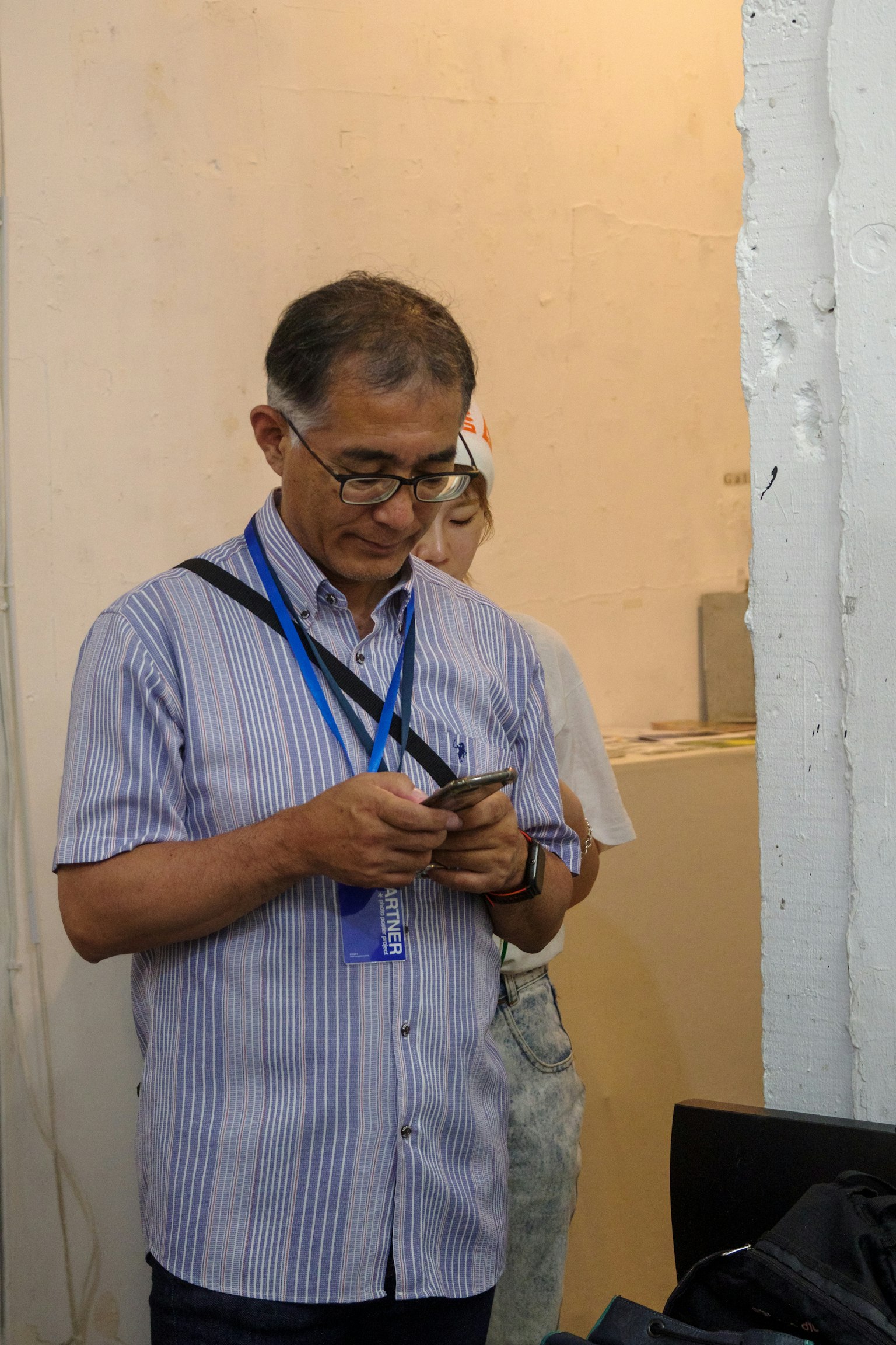 Un uomo che usa uno smartphone con un'altra persona sullo sfondo