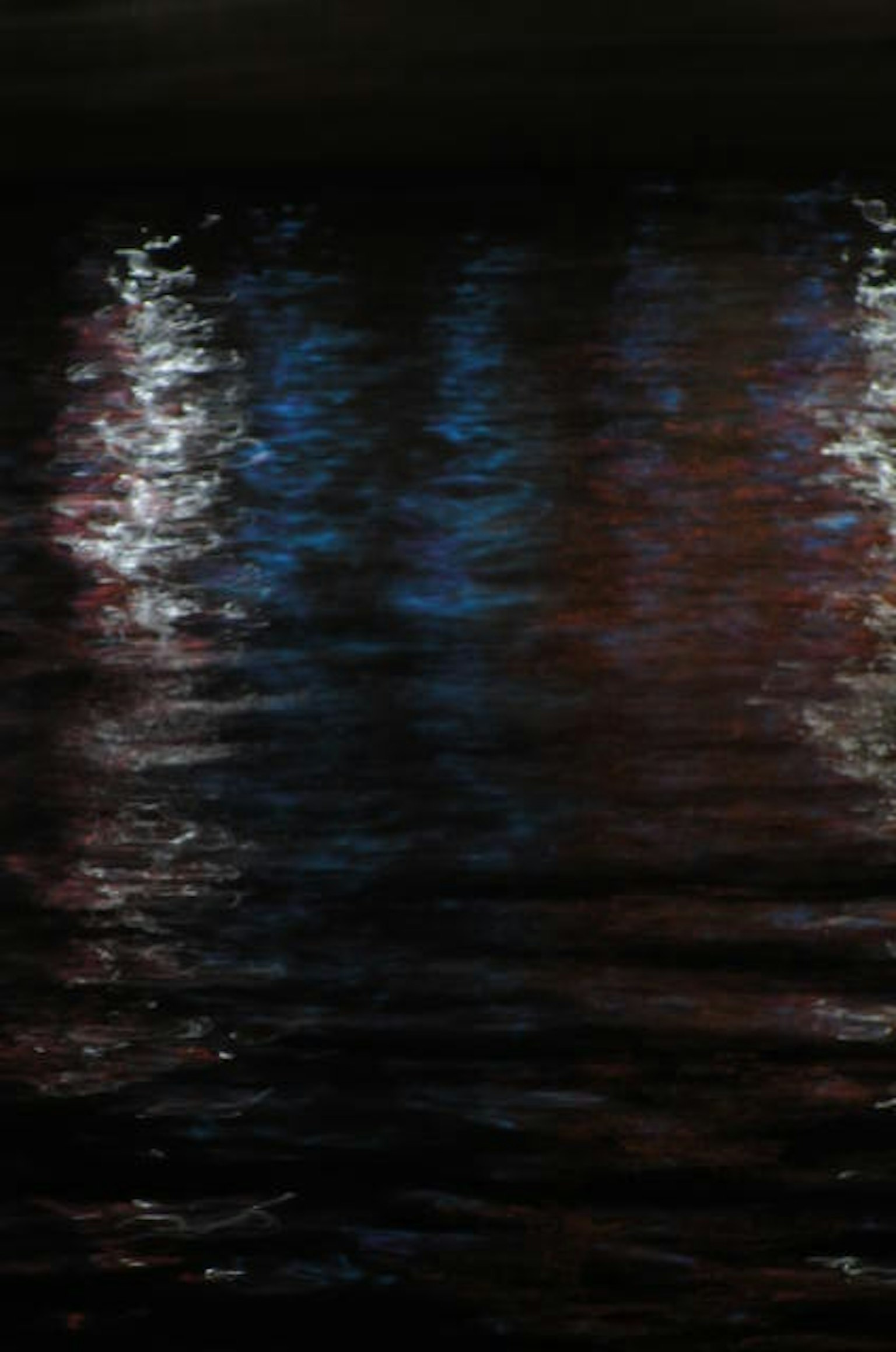 Refleksi warna-warni cahaya di permukaan air gelap