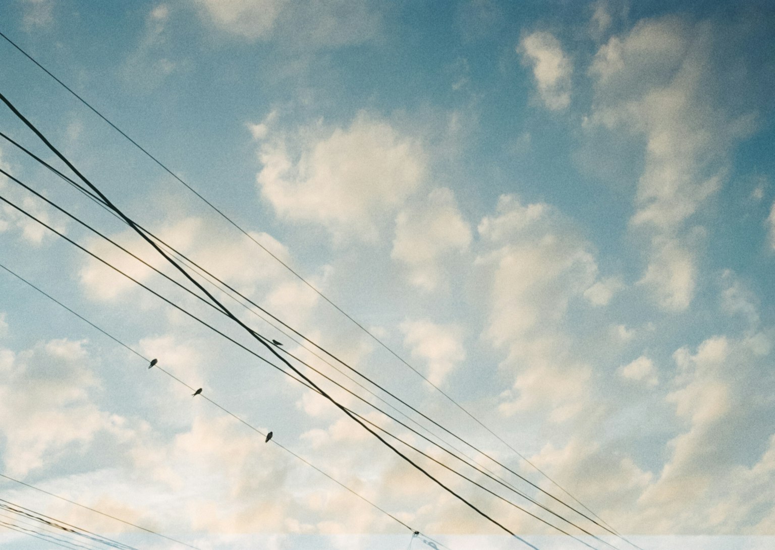 Silhouette de lignes électriques contre un ciel bleu avec des nuages