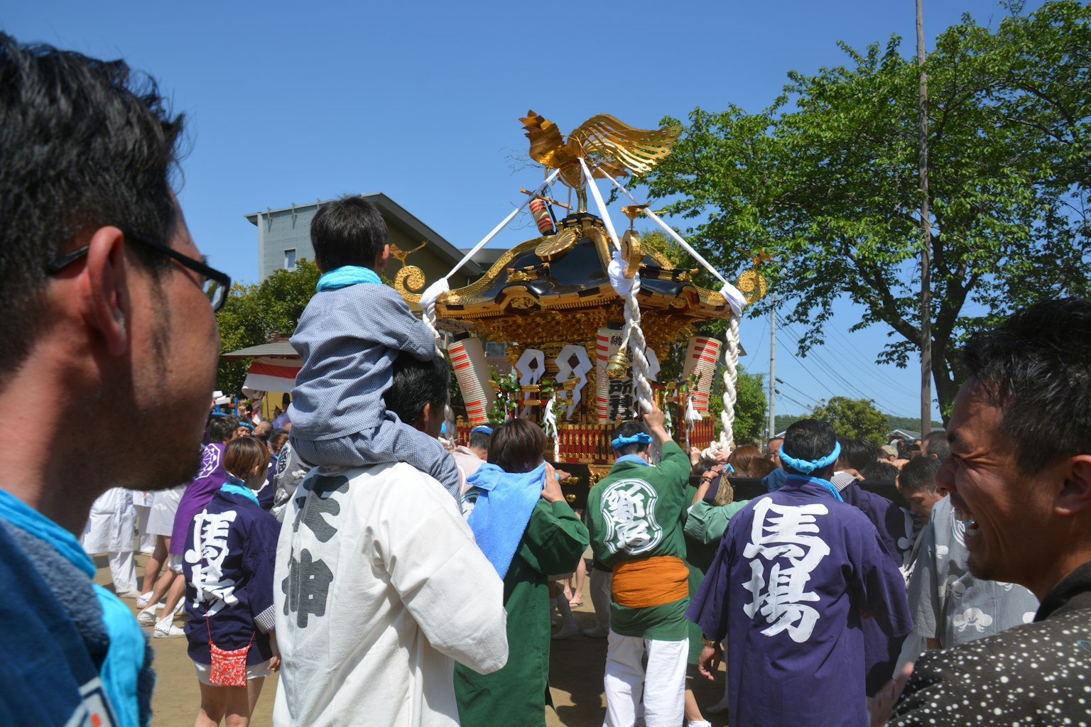 Người tham gia lễ hội đang mang mikoshi với trẻ em và trang phục truyền thống có thể nhìn thấy