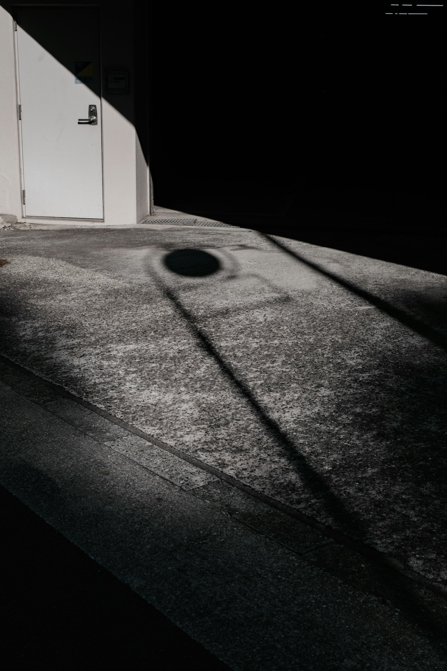 Photo of a white door and textured ground with shadows against a dark background