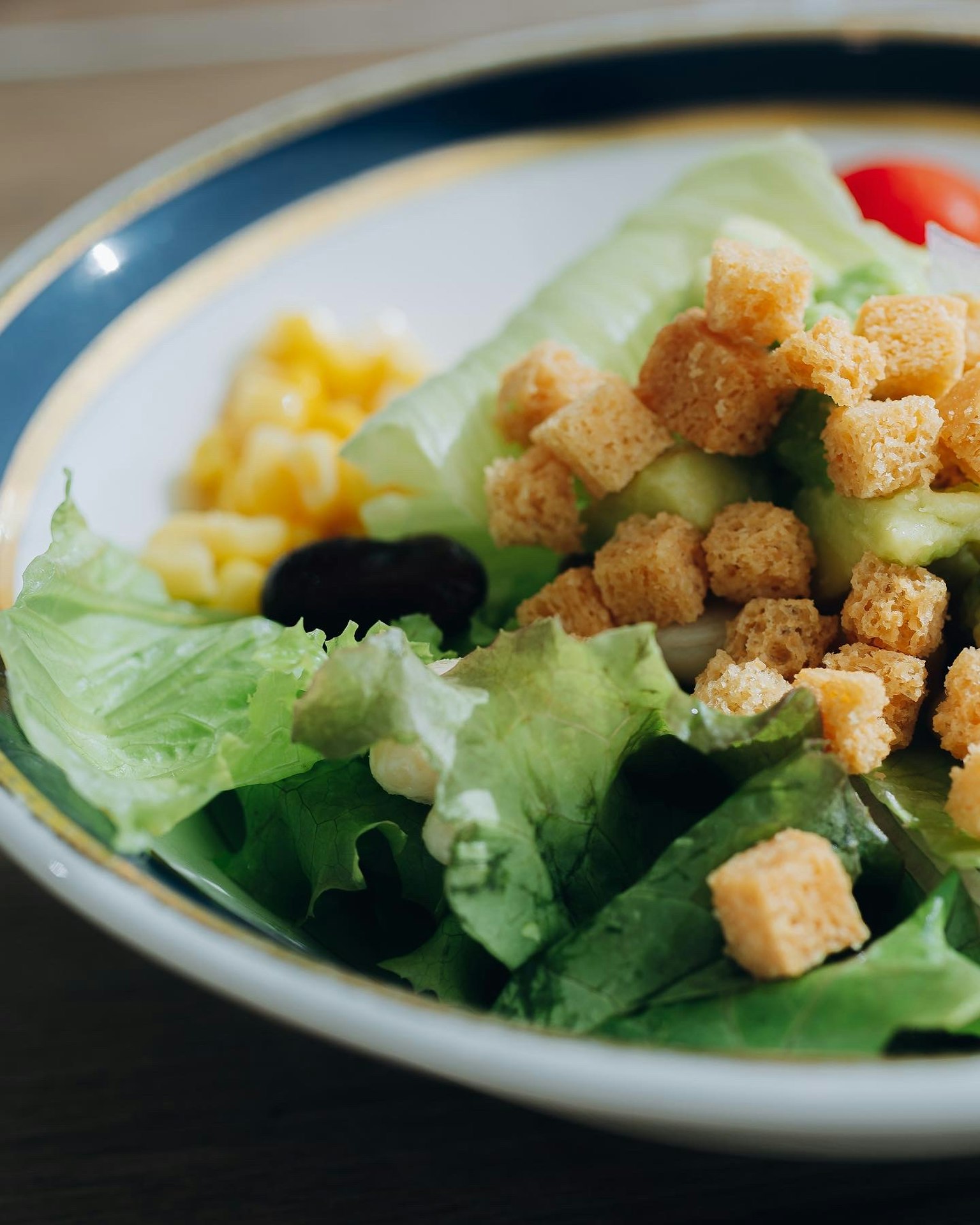 Một đĩa salad có xà lách bánh mì nướng cà chua và ngô