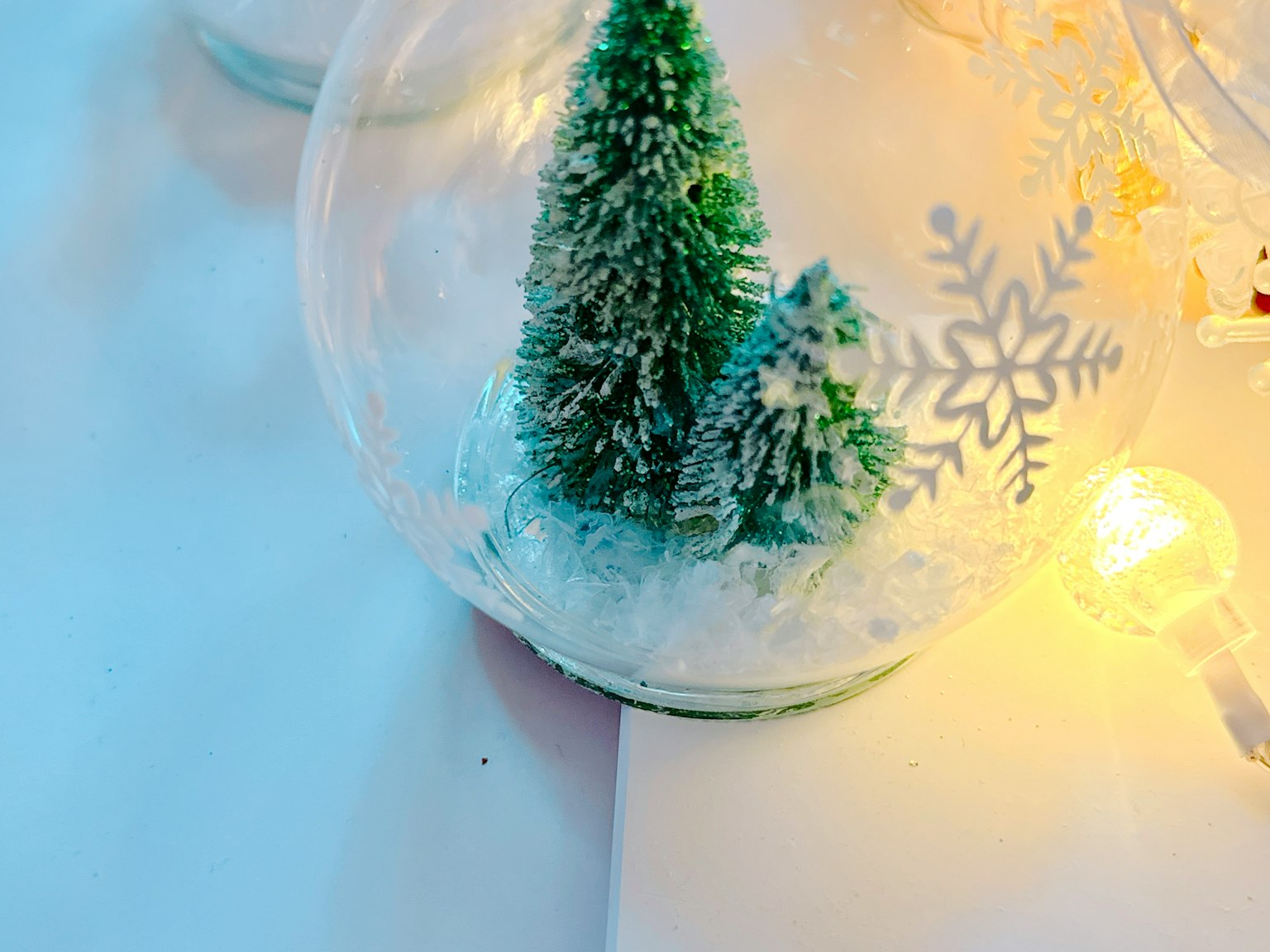 Adorno de vidrio con un árbol de Navidad verde y copos de nieve