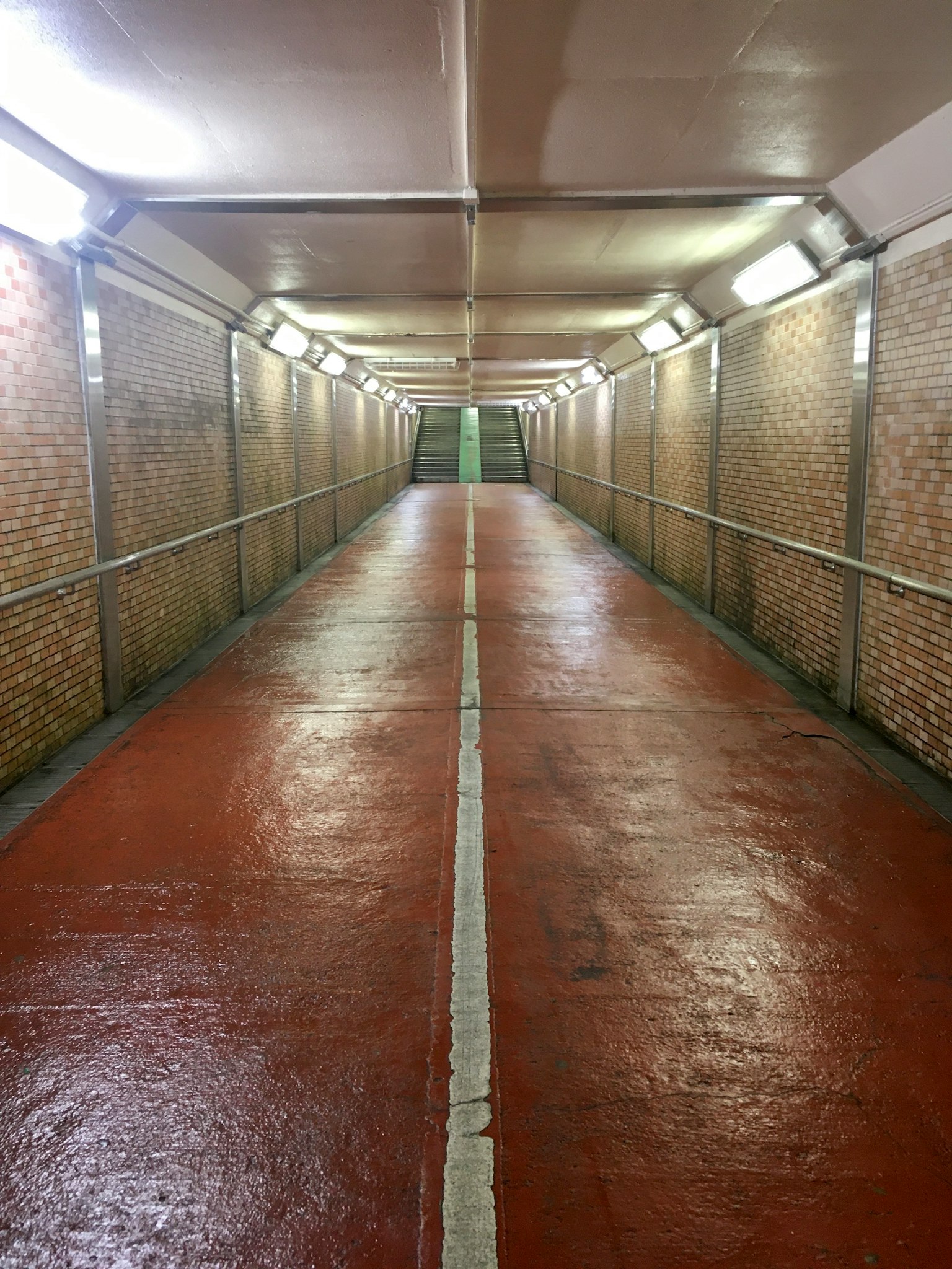 Interior of a long corridor with red floor and tiled walls