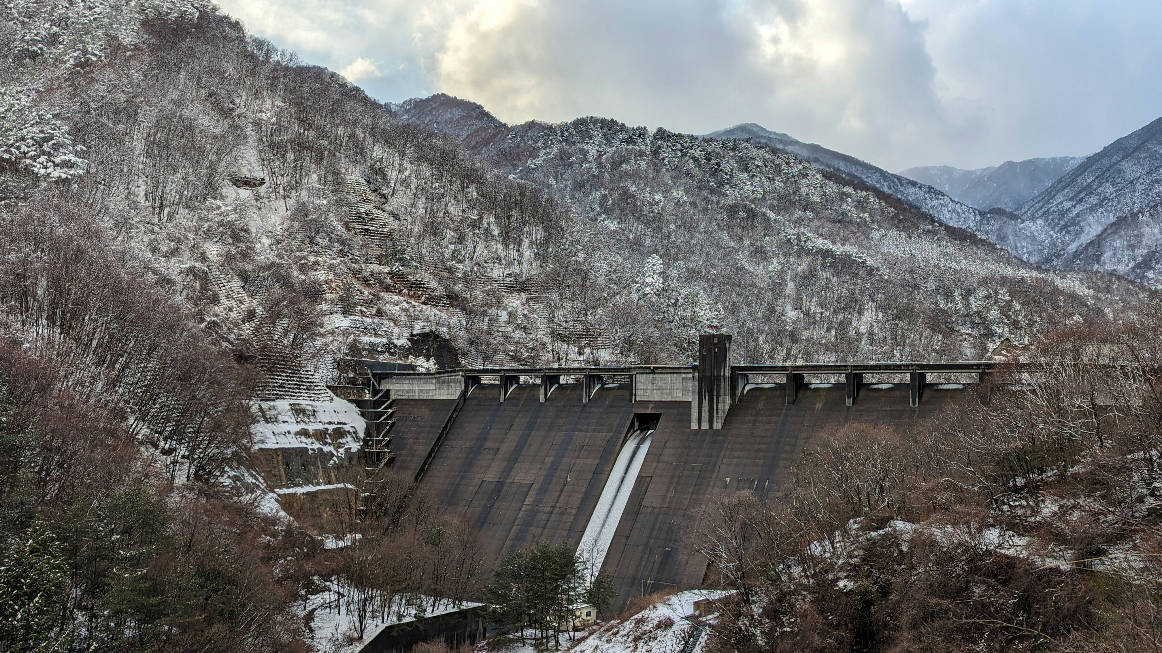 雪の残る山間のダムと堤体