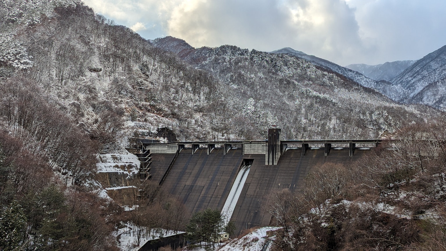Staumauer zwischen schneebedeckten Bergen
