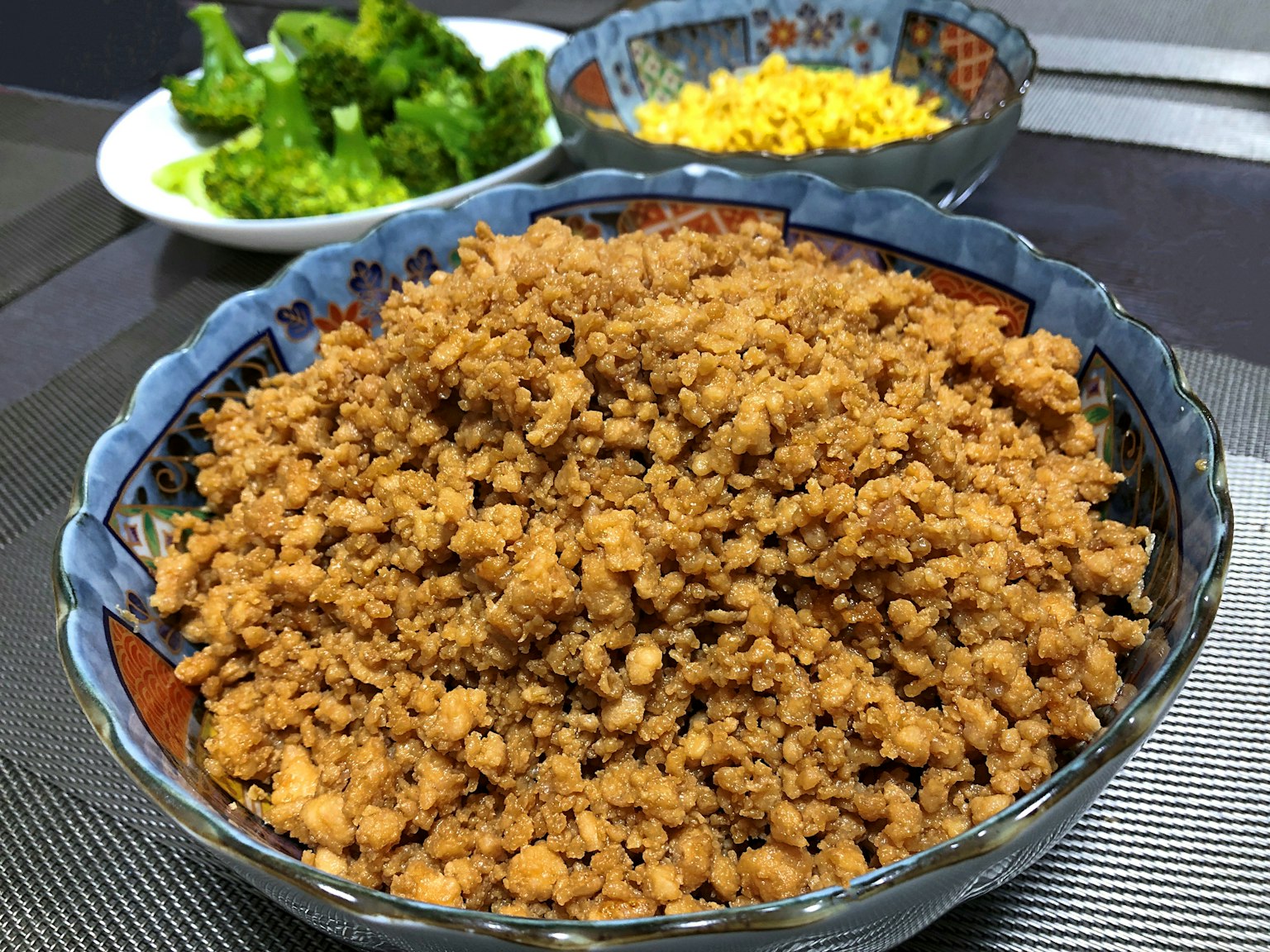Tazón de carne molida marrón con guarniciones de brócoli y queso rallado
