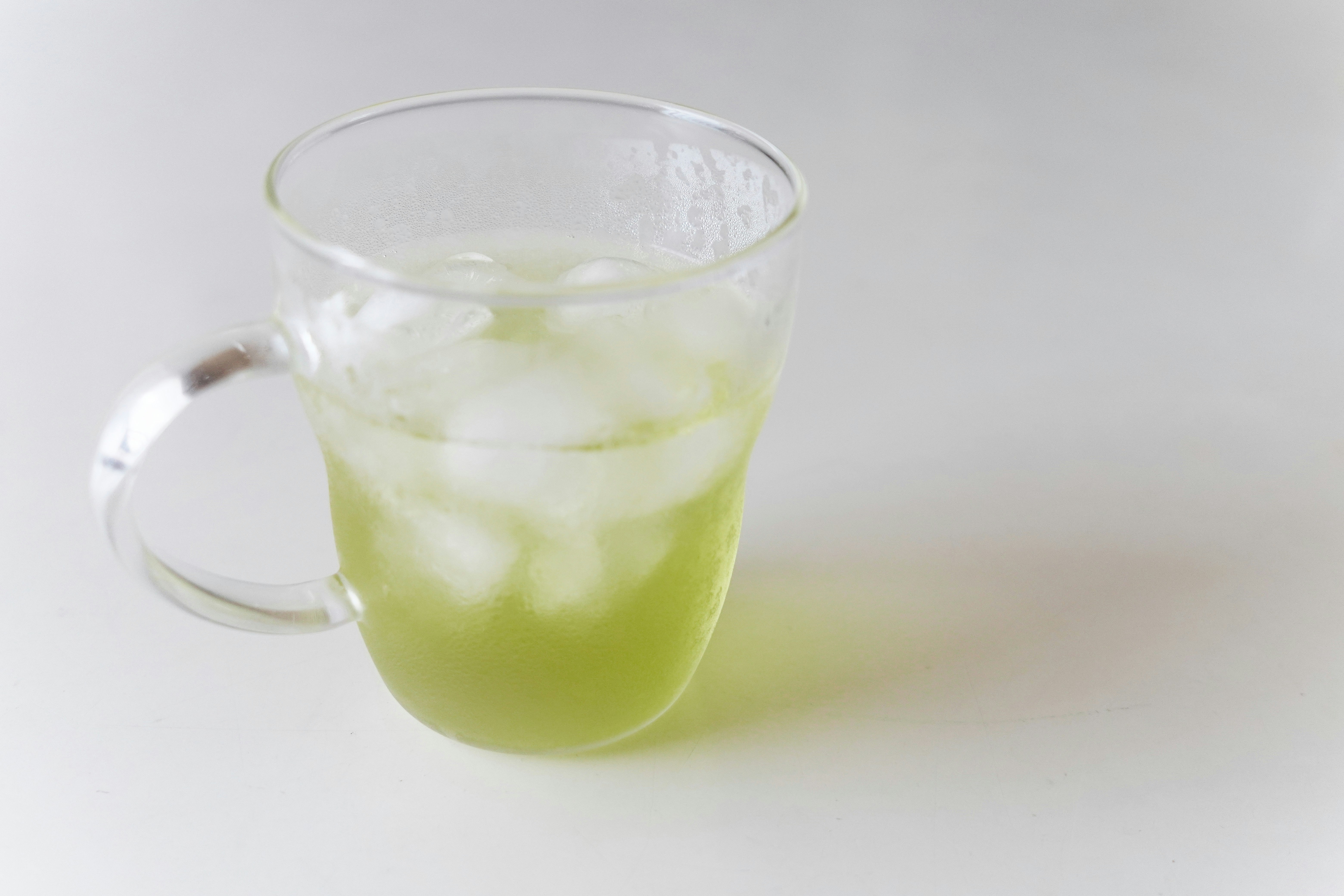 緑色の飲み物が入った透明なガラスのマグカップのアップ