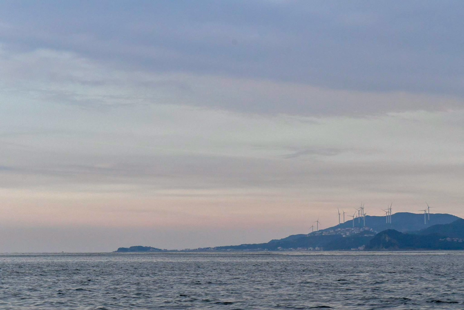 平静的海面与山上的风力涡轮机可见