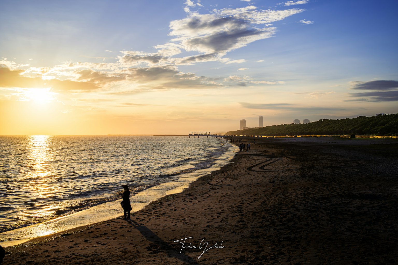Silhouette einer Person, die am Strand bei Sonnenuntergang steht, mit lebhaften Himmelstönen