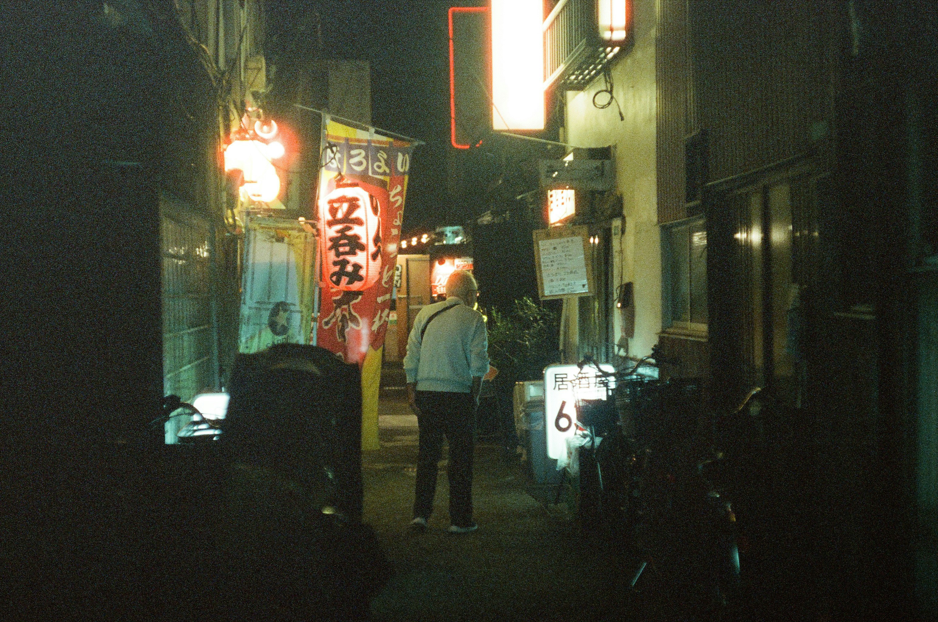 enseignes néon et silhouettes dans une ruelle de bars