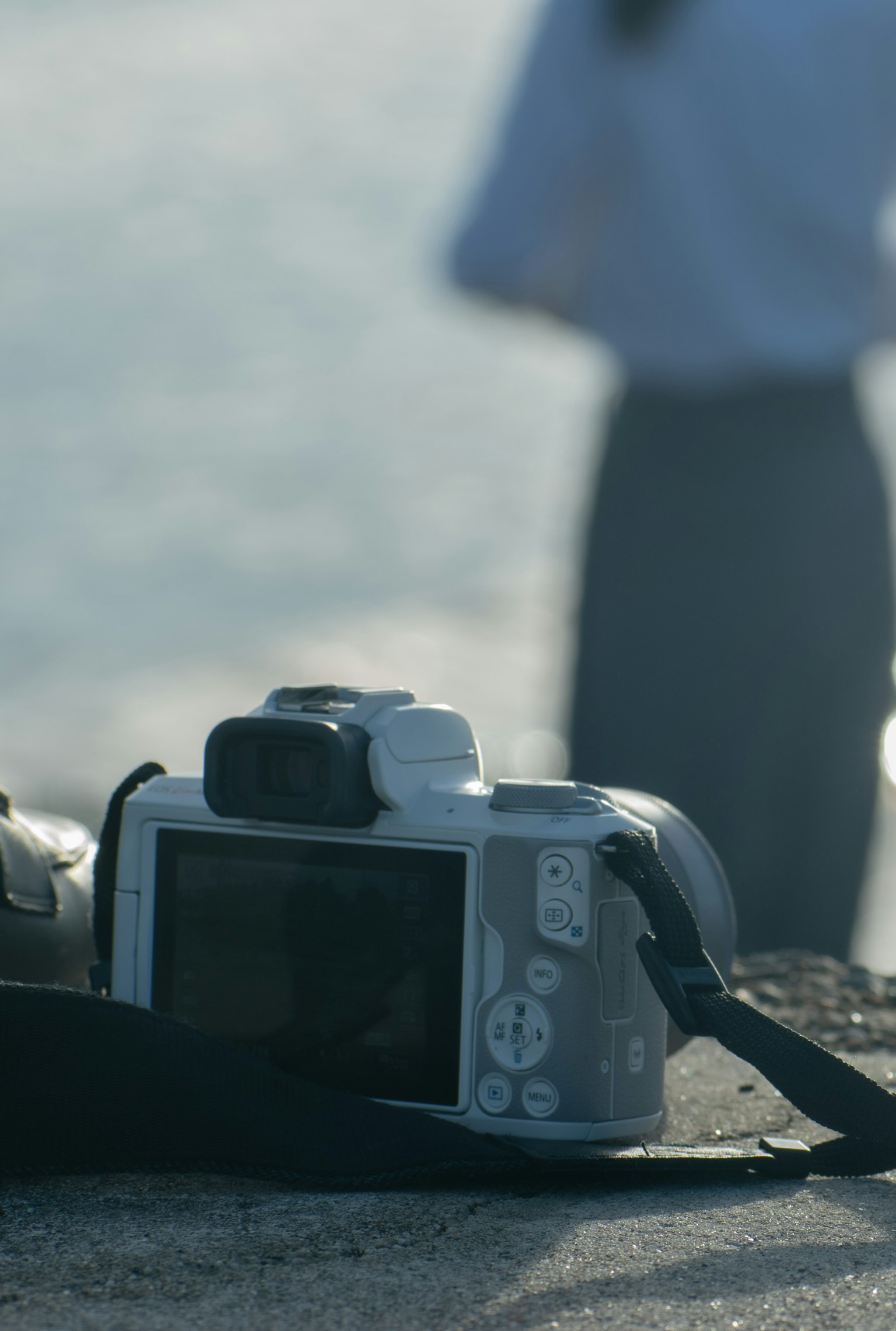 Macchina fotografica posizionata vicino al mare con una figura sfocata sullo sfondo