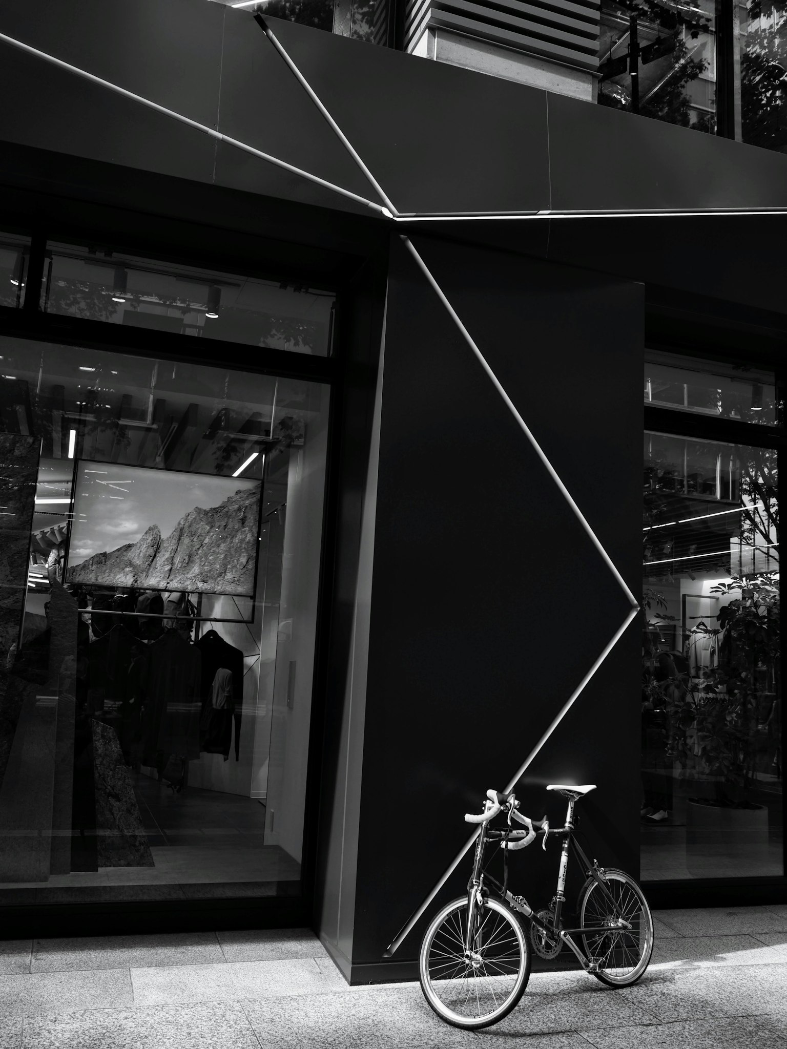 Una bicicletta appoggiata a un muro nero geometrico con angoli acuti e design moderno