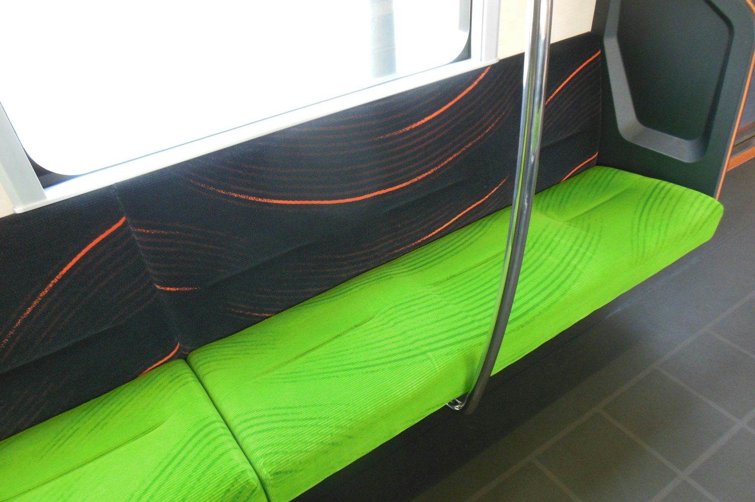 Interior kendaraan transportasi publik dengan kursi hijau cerah dan dinding hitam