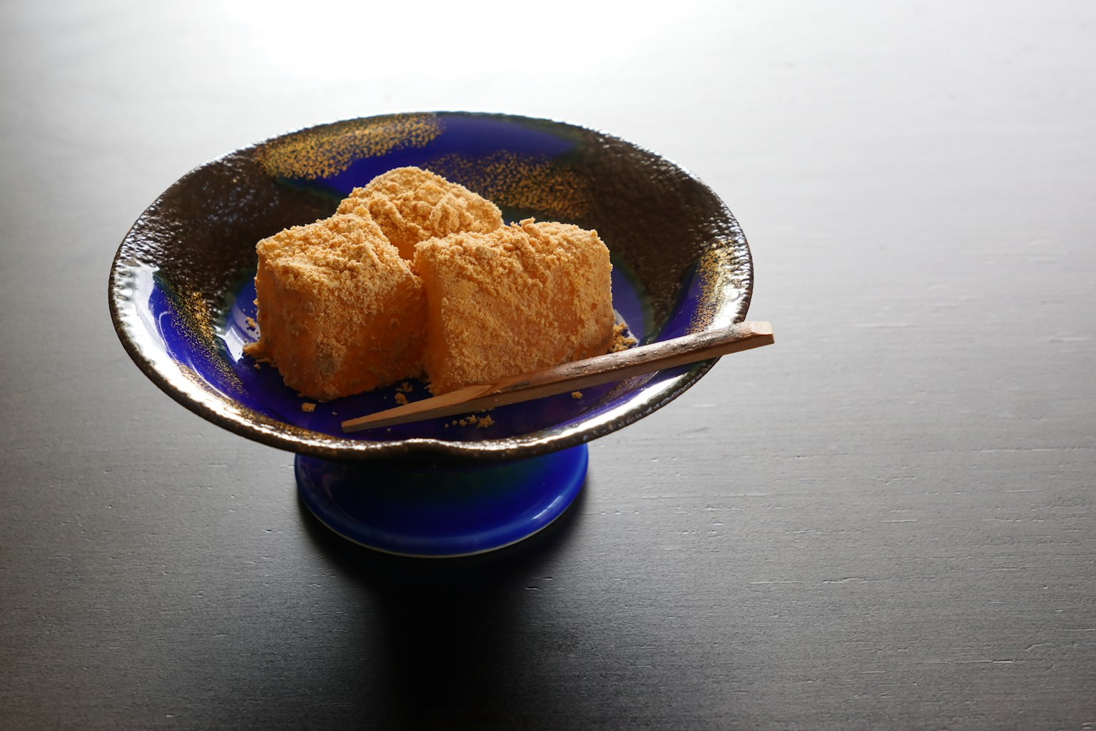 Tre blocchi di tofu su un piatto blu con le bacchette