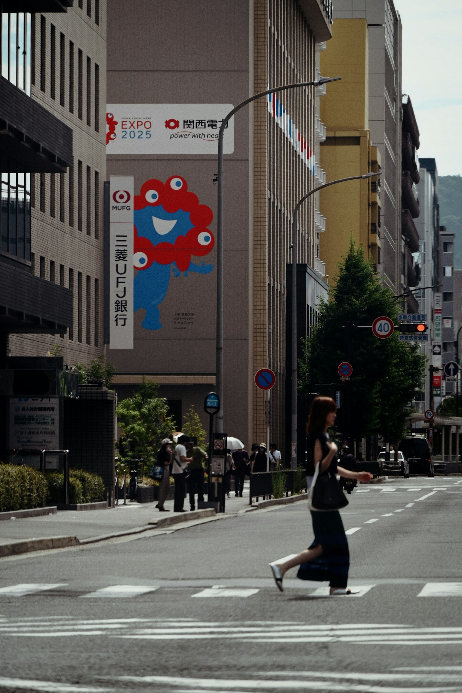 Una mujer cruzando la calle con un anuncio colorido de fondo