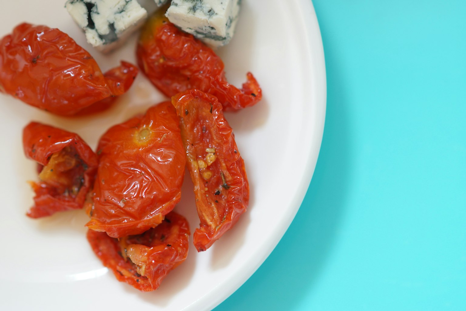 Dried tomatoes and blue cheese on a white plate