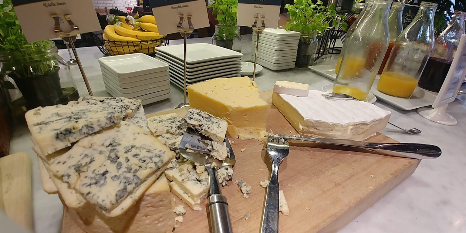 Un tagliere di legno con vari tipi di formaggio e posate