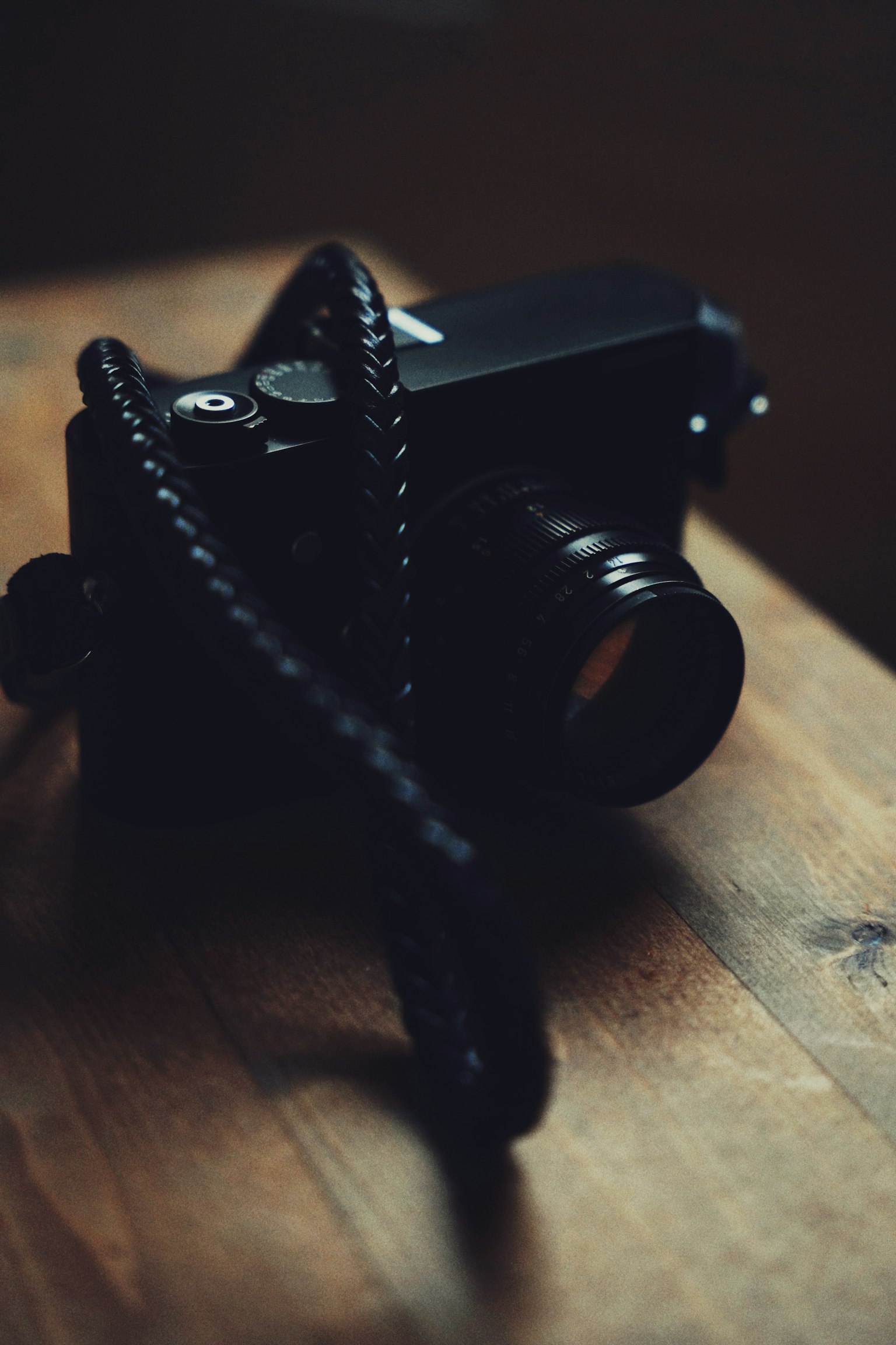 Gros plan d'un appareil photo noir avec une sangle reposant sur une table en bois
