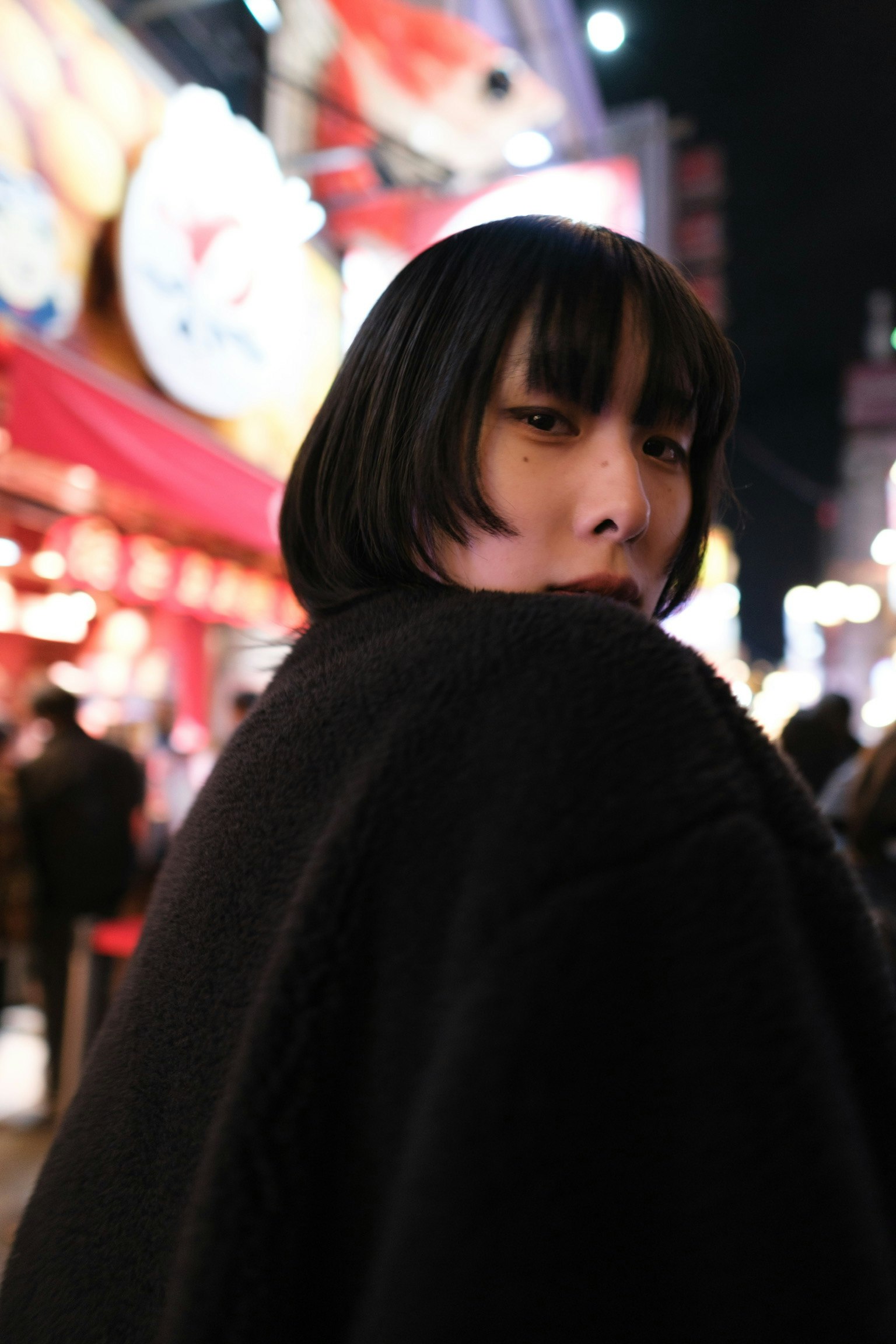 夜の屋台通りで黒いコートの女性