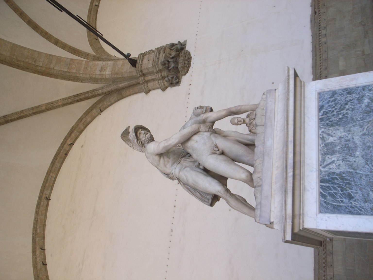 White marble sculpture displayed in an art museum featuring male and female figures