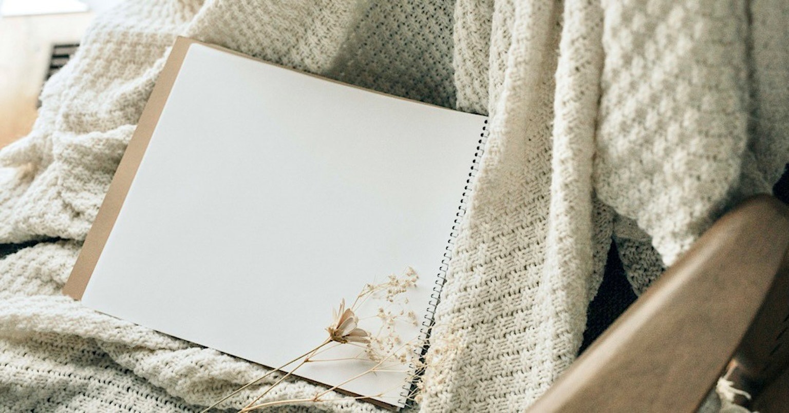 Un cuaderno en blanco sobre una manta color crema