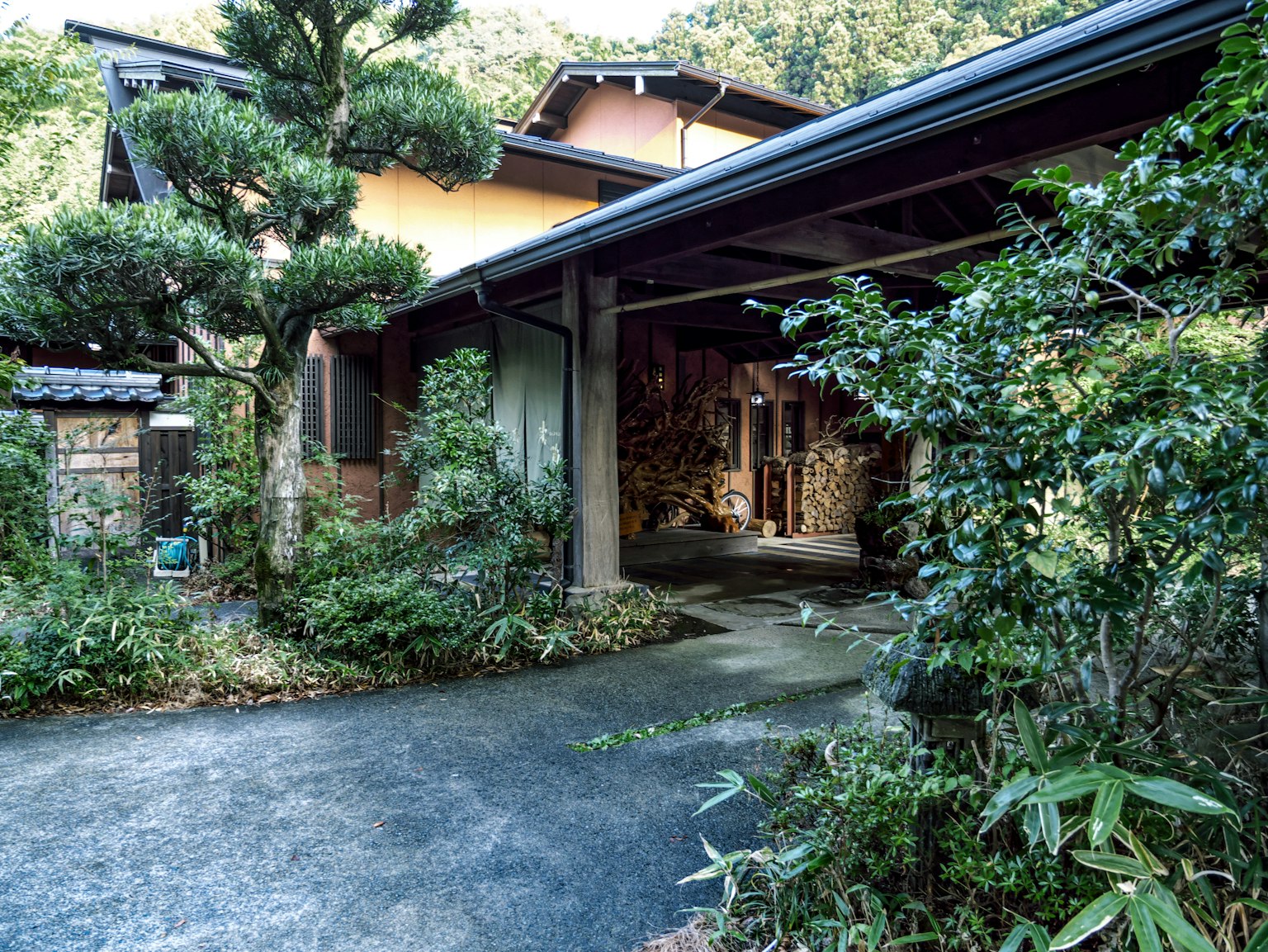 Entrée d'une maison japonaise traditionnelle entourée de verdure luxuriante et de plantes