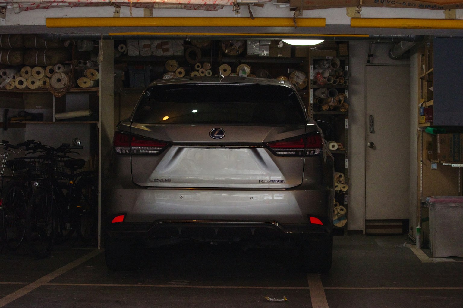 一輛銀色SUV停在車庫內，周圍有捲起的材料