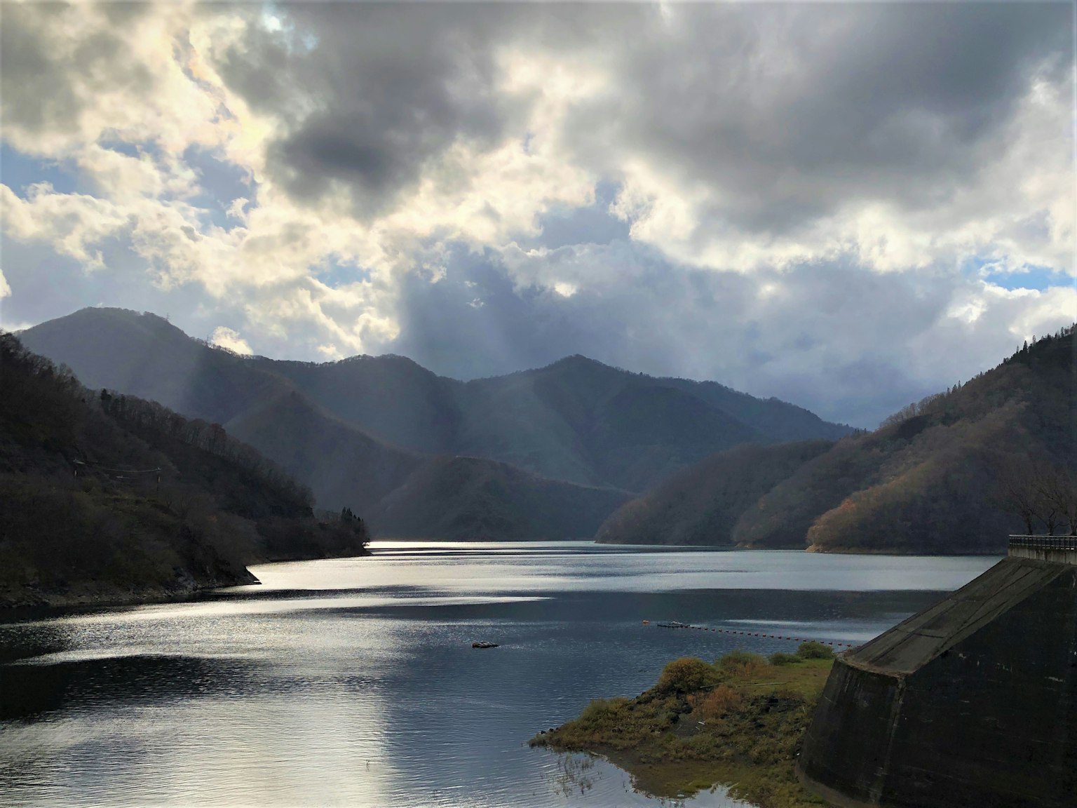 Malersiche Aussicht auf Berge und See mit Lichtstrahlen durch die Wolken