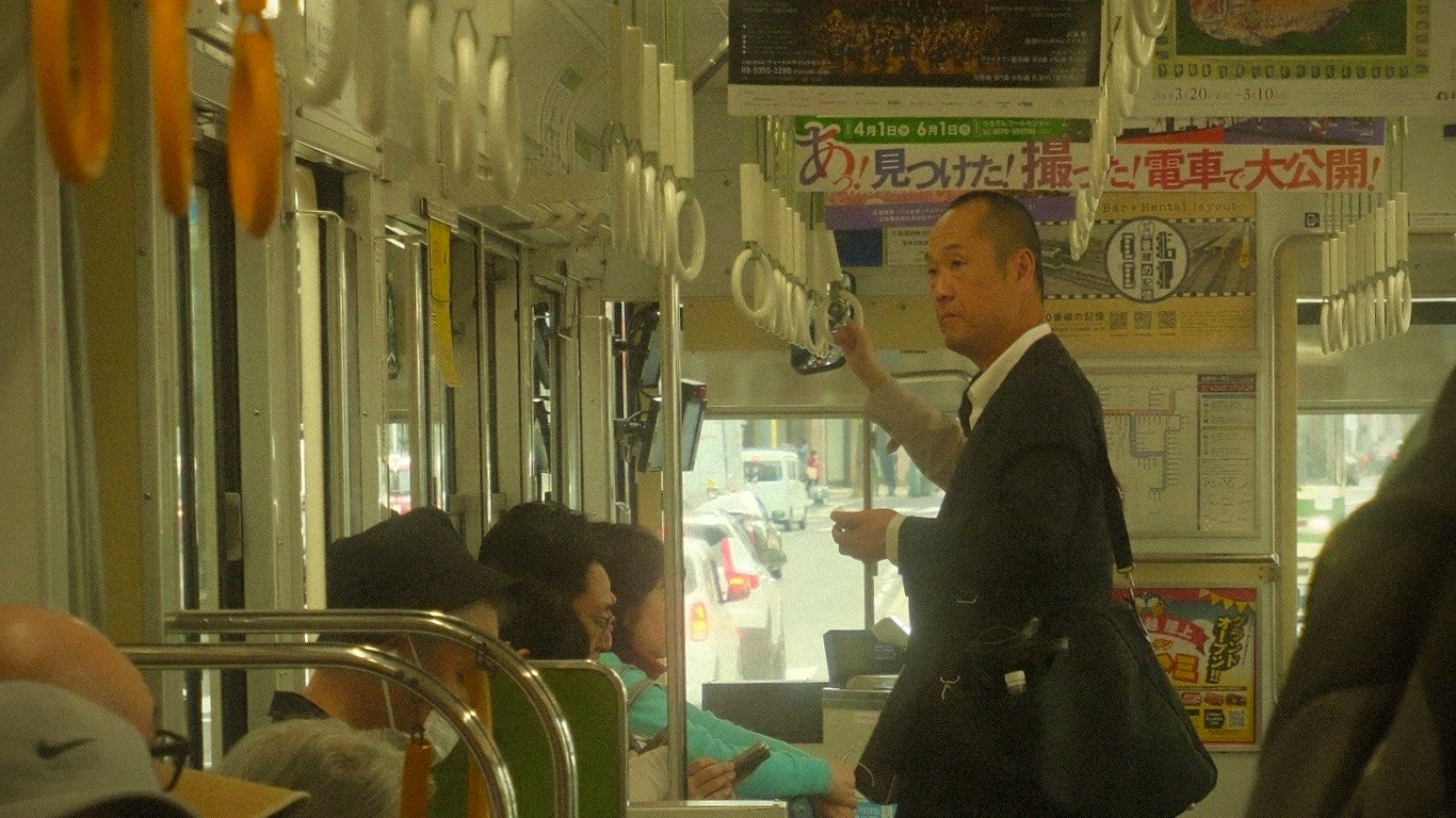 车厢内，穿西装的男子抓着扶手并有乘客的场景