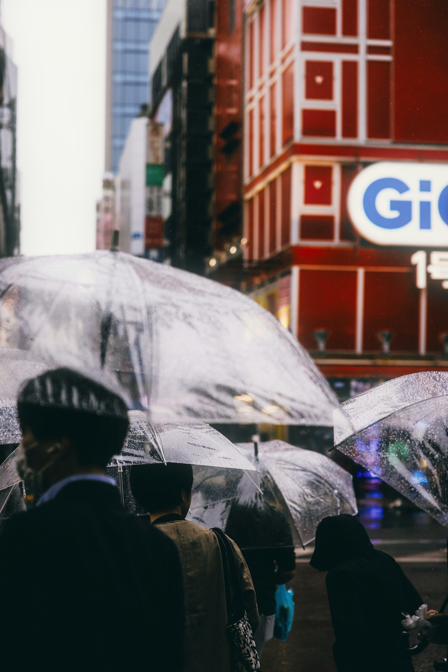 Des personnes marchant avec des parapluies transparents dans une scène urbaine