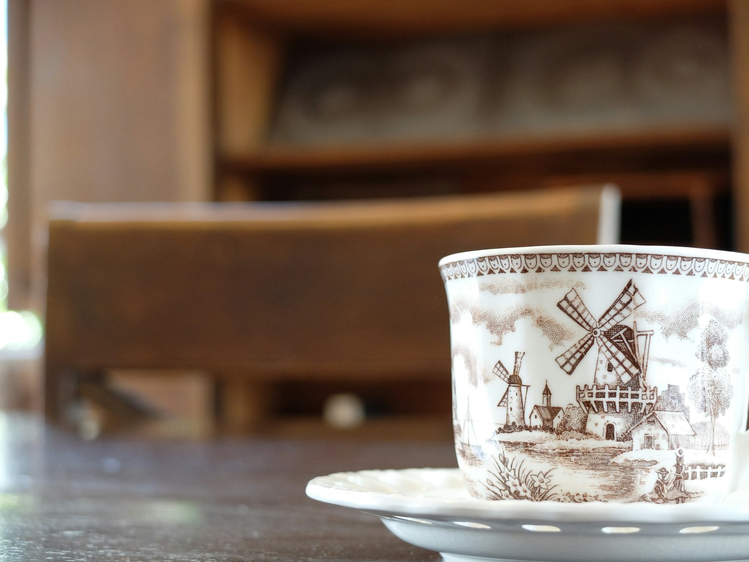 Une tasse avec un motif de moulin à vent posée sur une soucoupe sur une table en bois