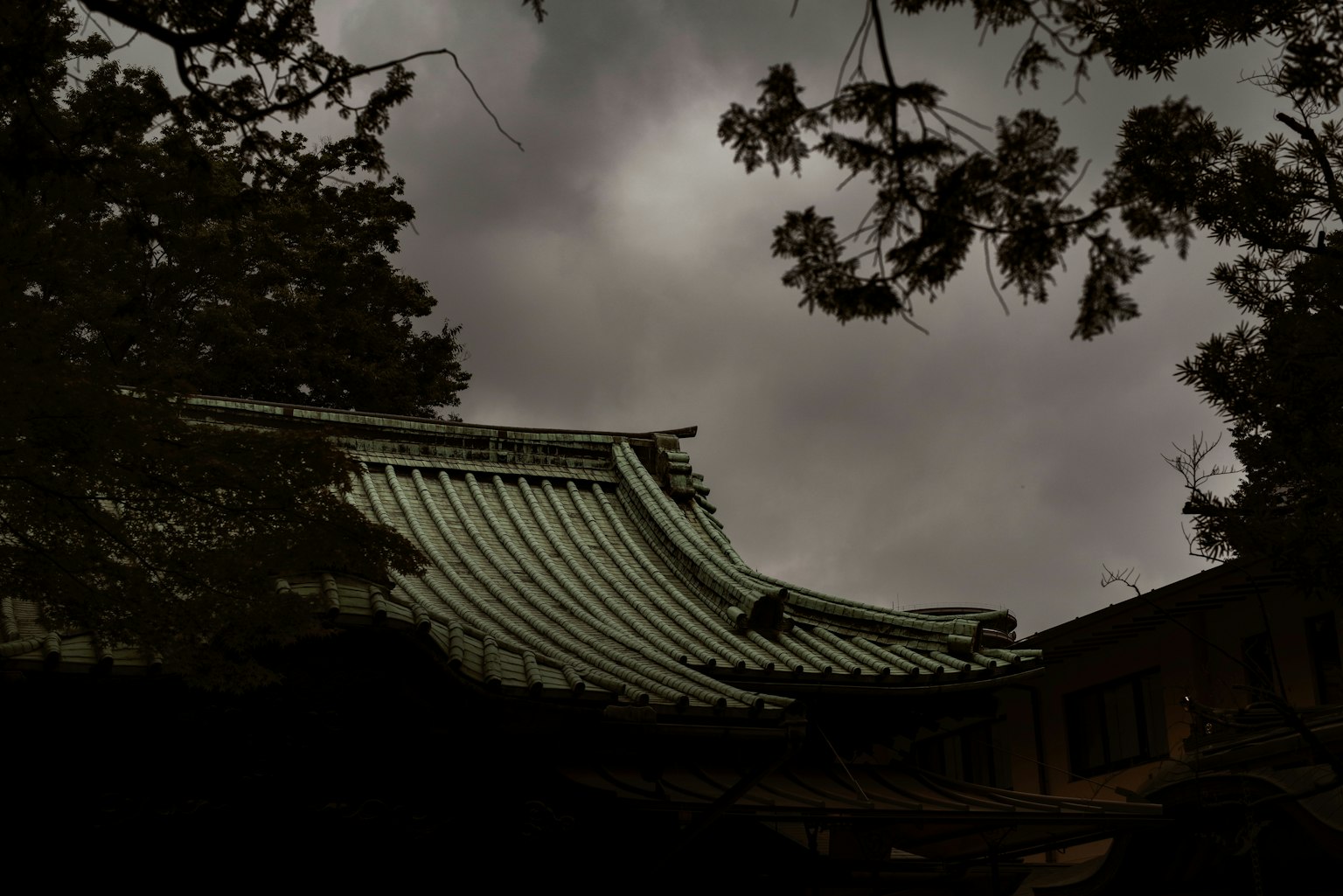 Parte de un techo de un edificio japonés tradicional bajo nubes oscuras
