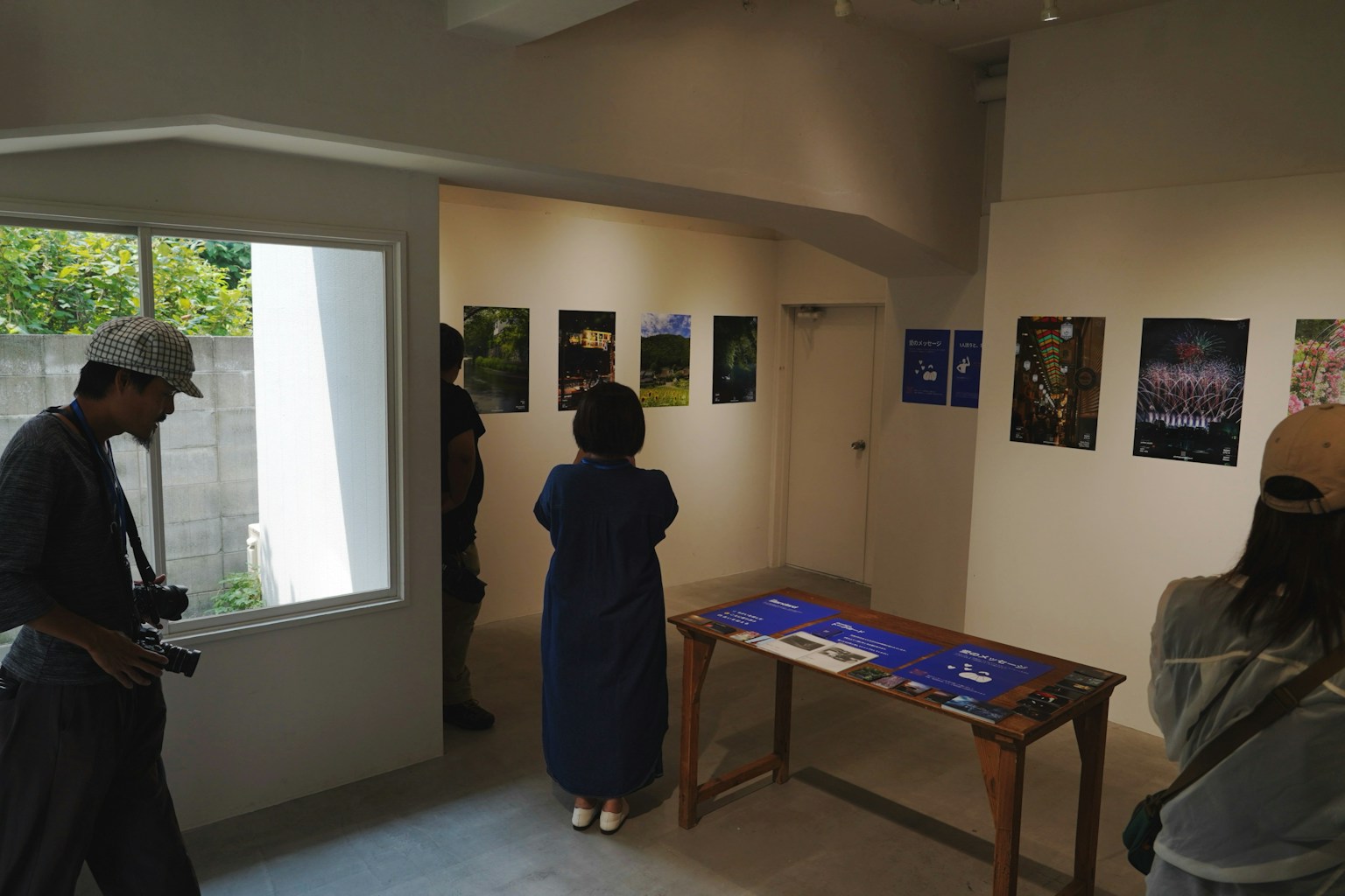 アートギャラリーの内部で写真を鑑賞する人々がいる様子 窓から自然光が差し込む