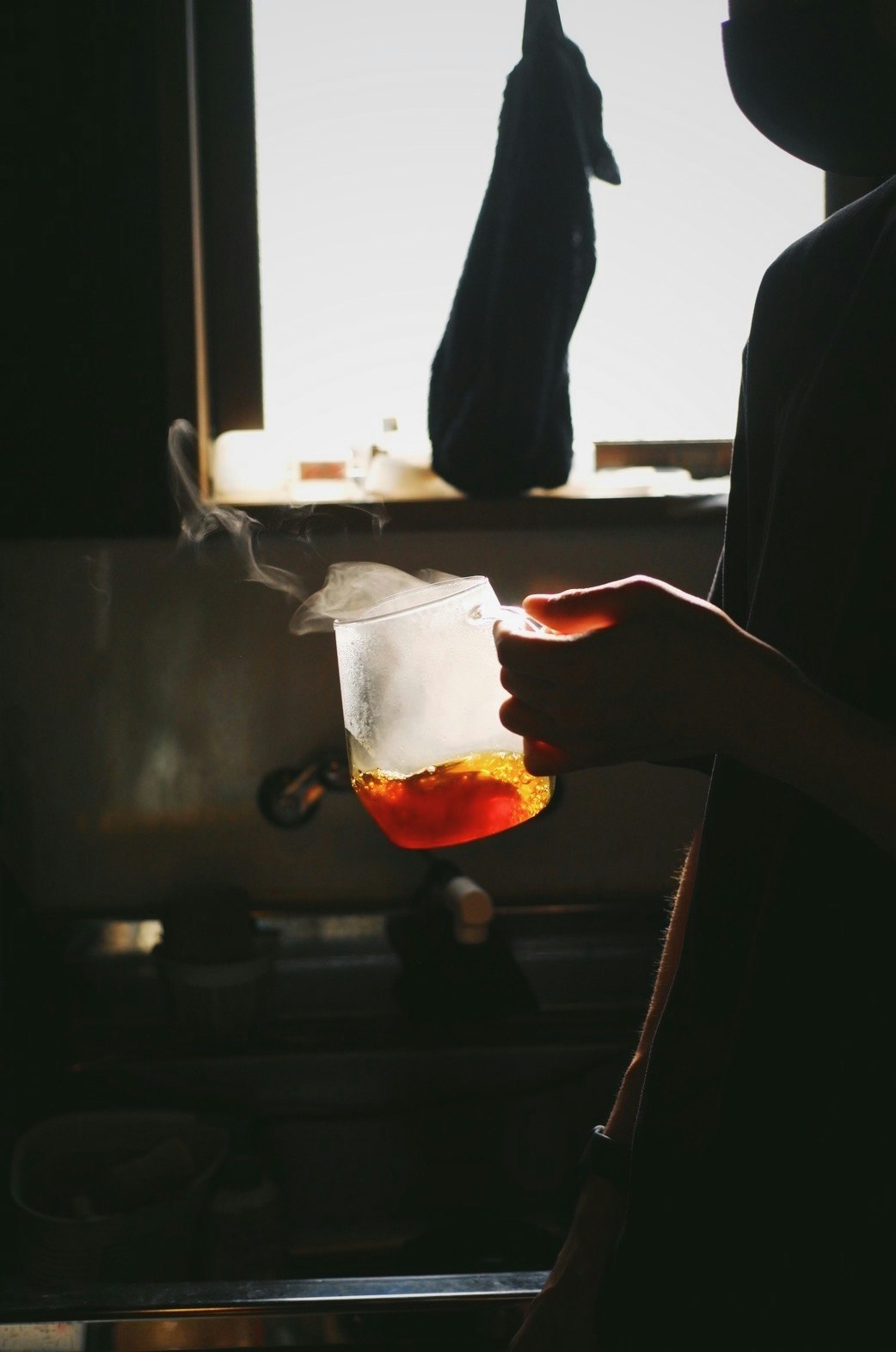 A hand pouring coffee into a cup on a table in an evening indoor setting
