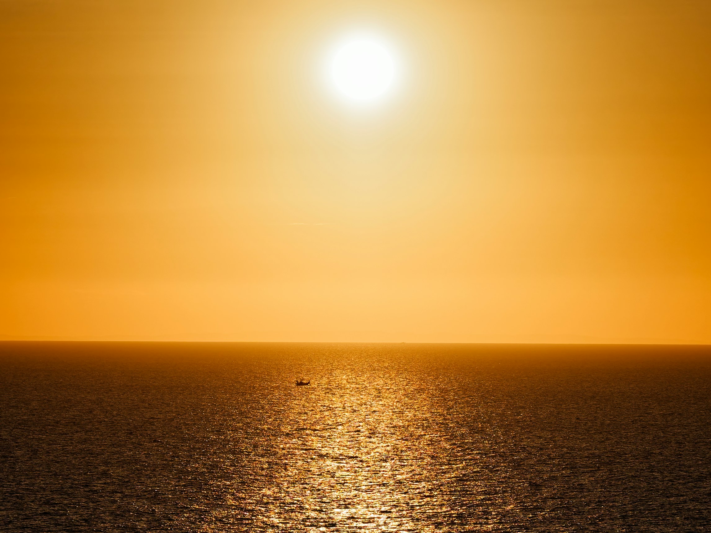 水平線に沈む夕日と海面の光の道