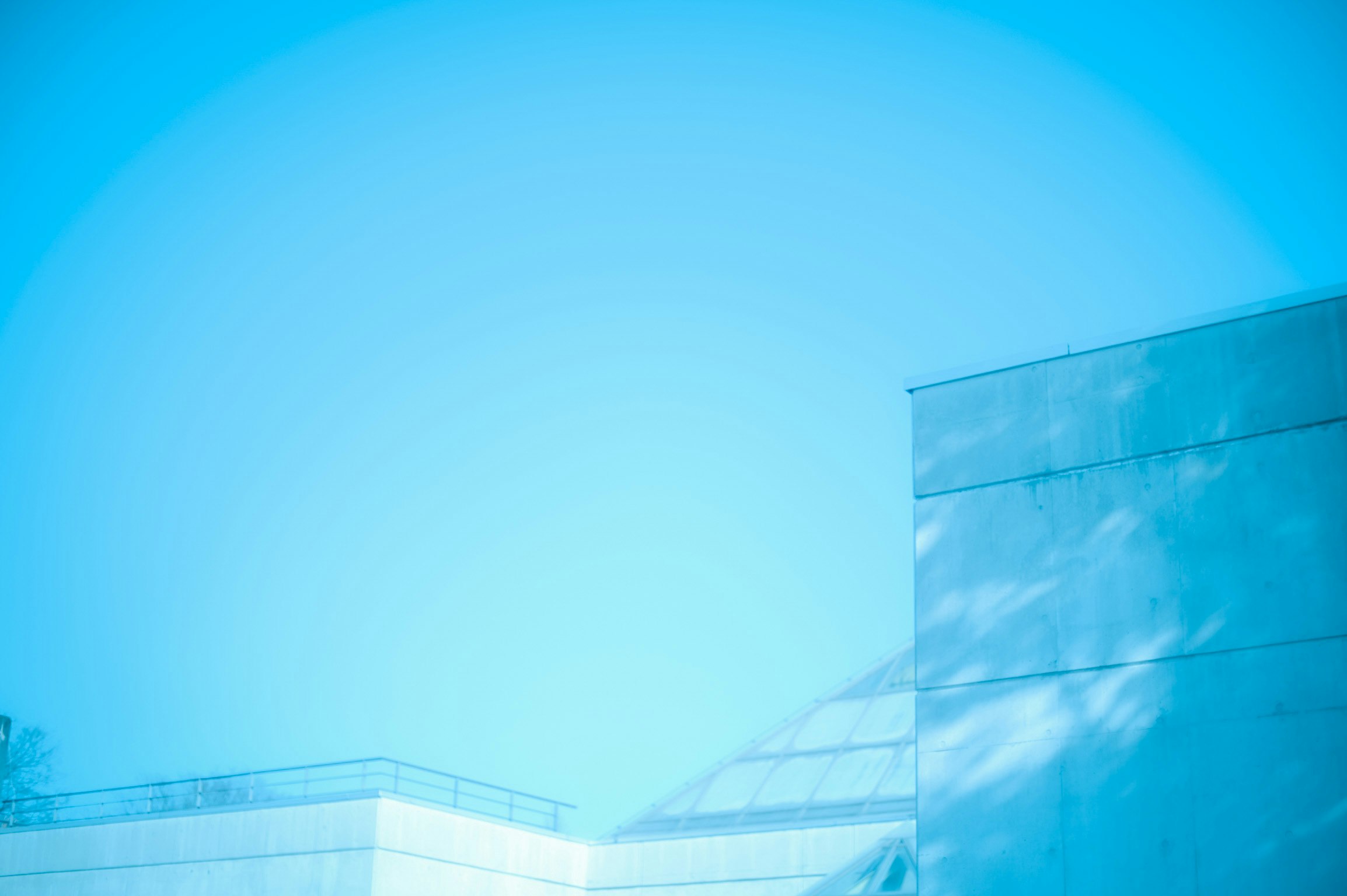 glass building and curved roof under a blue sky