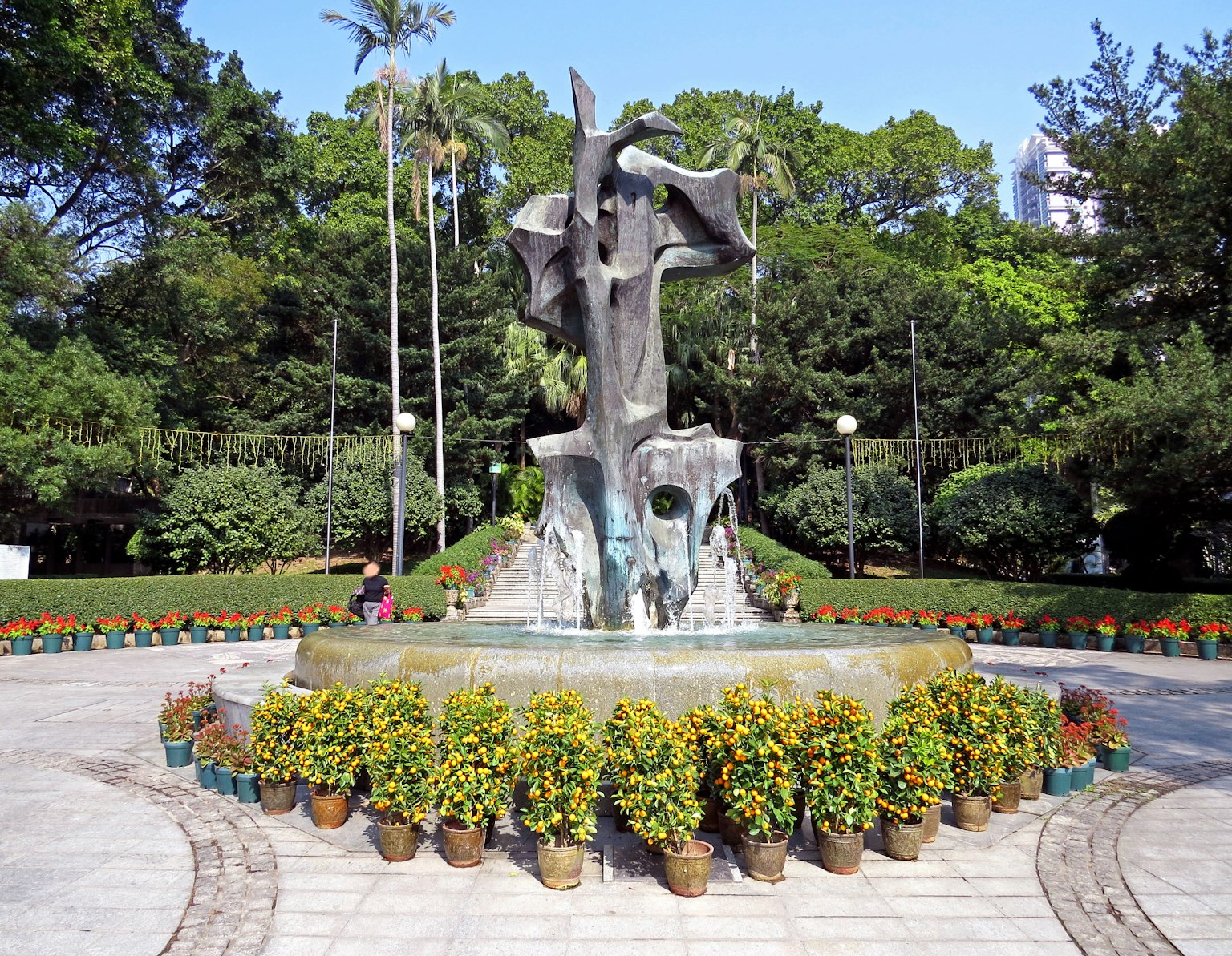Bellissima fontana al centro di un parco circondata da vasi di fiori colorati