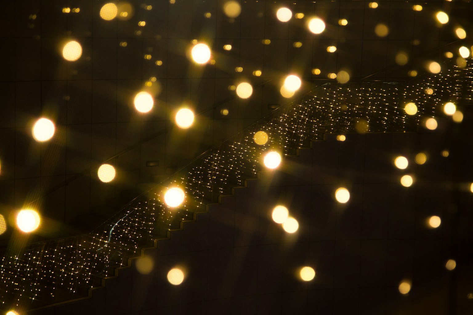 Eine fließende Linie aus funkelnden goldenen Lichtpunkten vor einem dunklen Hintergrund