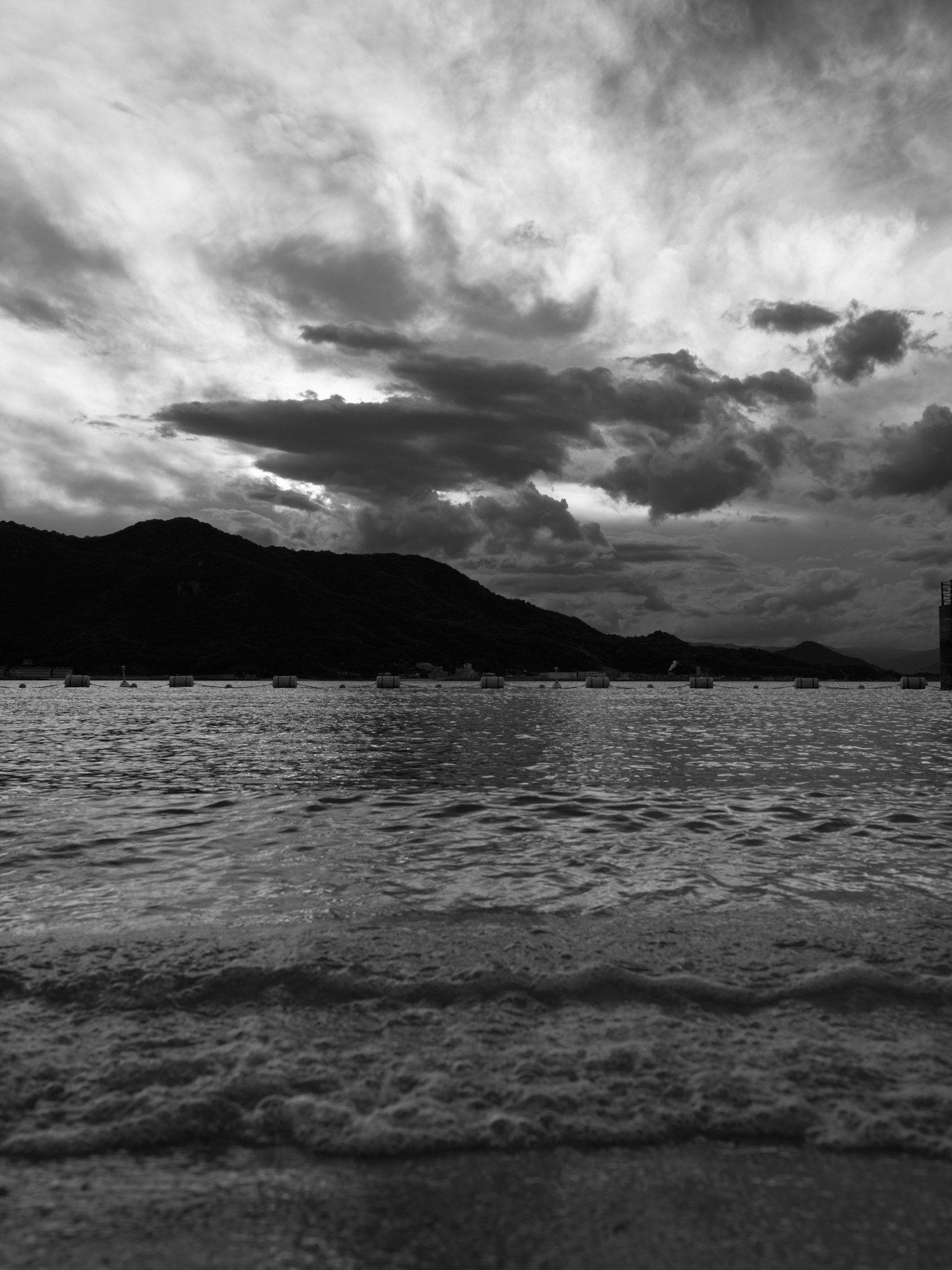 Meereslandschaft mit Bergen schwarz-weiß-Kontrast bewölkter Himmel