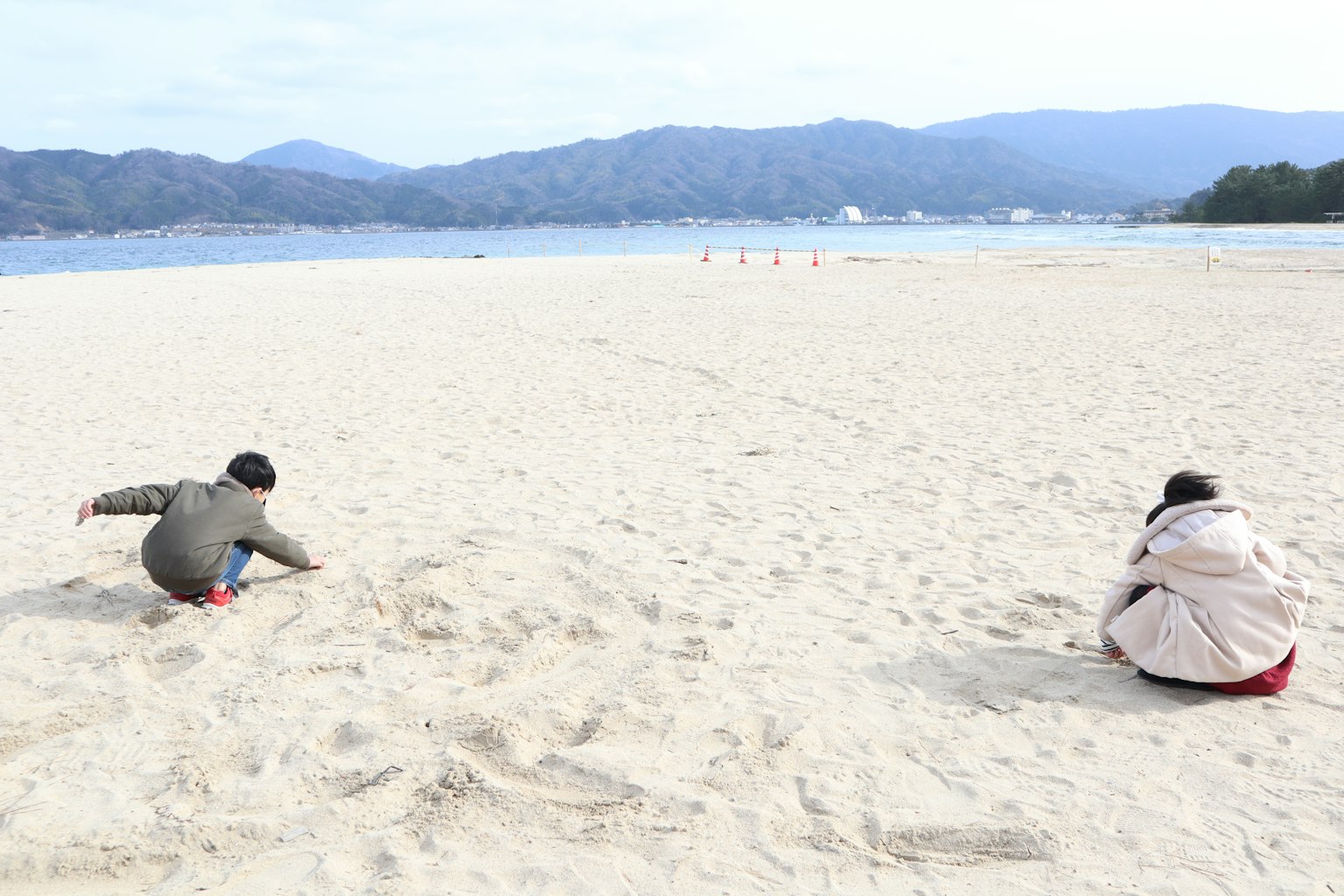 Deux enfants jouant sur la plage avec du sable et une vue panoramique sur la mer