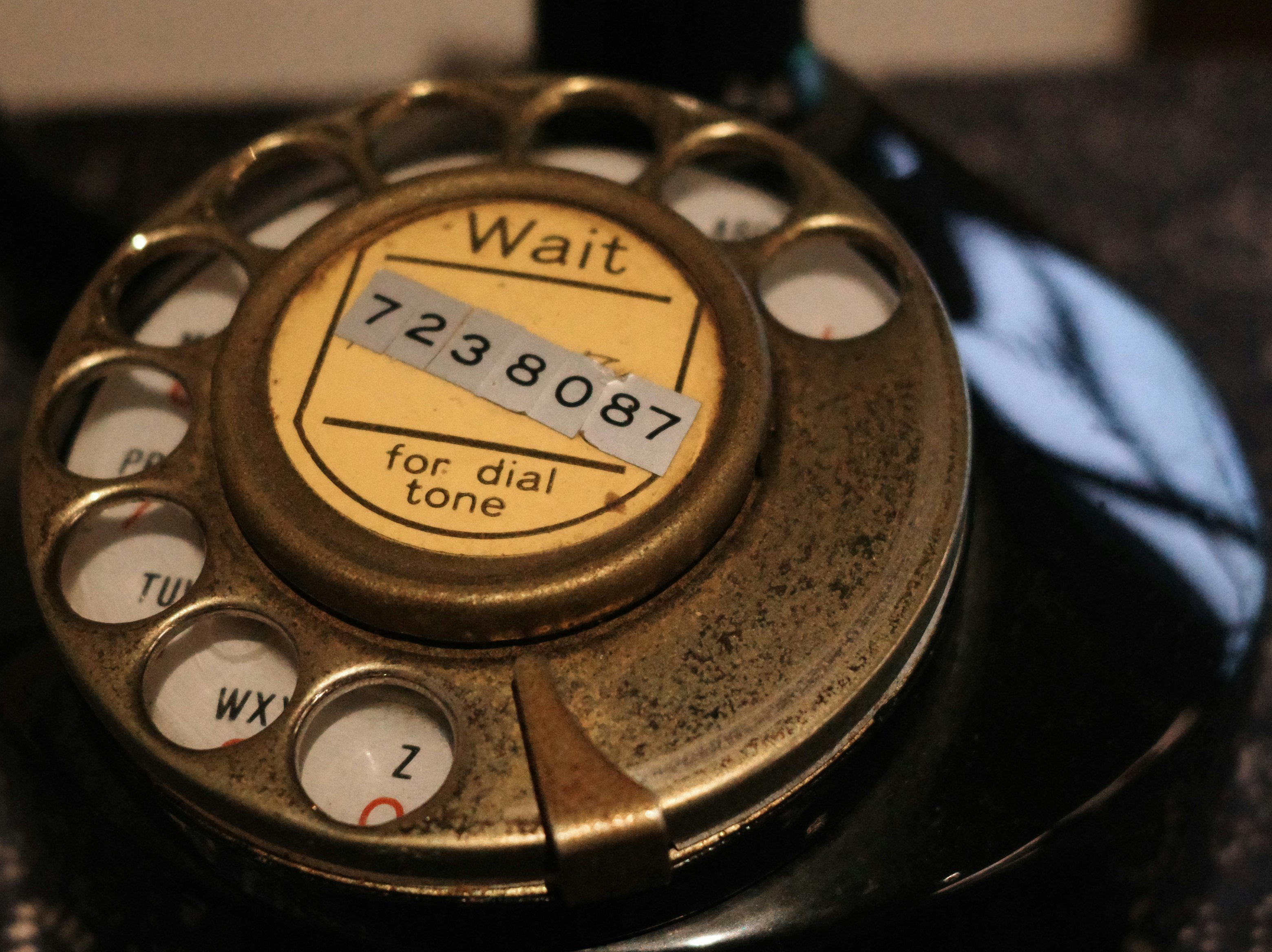 Close-up dial telepon putar dengan tulisan “Wait”