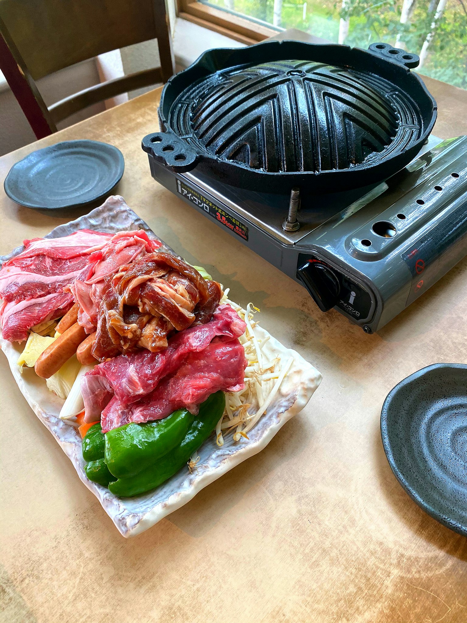 Grilled meat ingredients arranged on a table with a portable grill