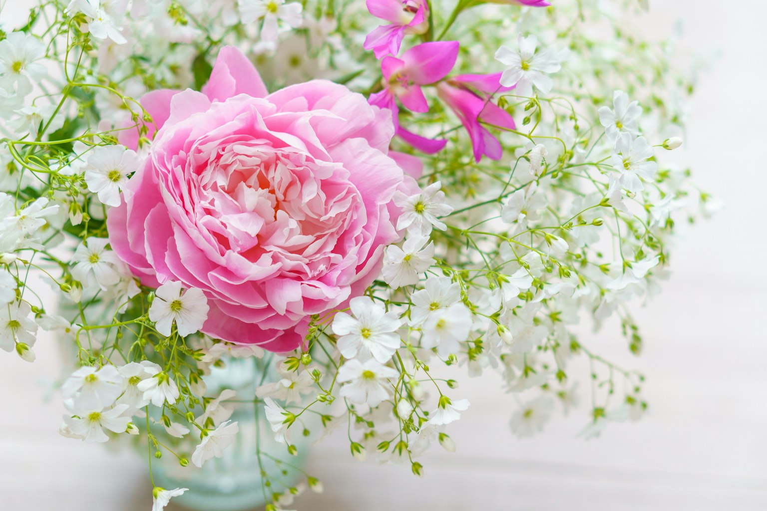 Un bouquet avec une rose rose et des fleurs blanches délicates