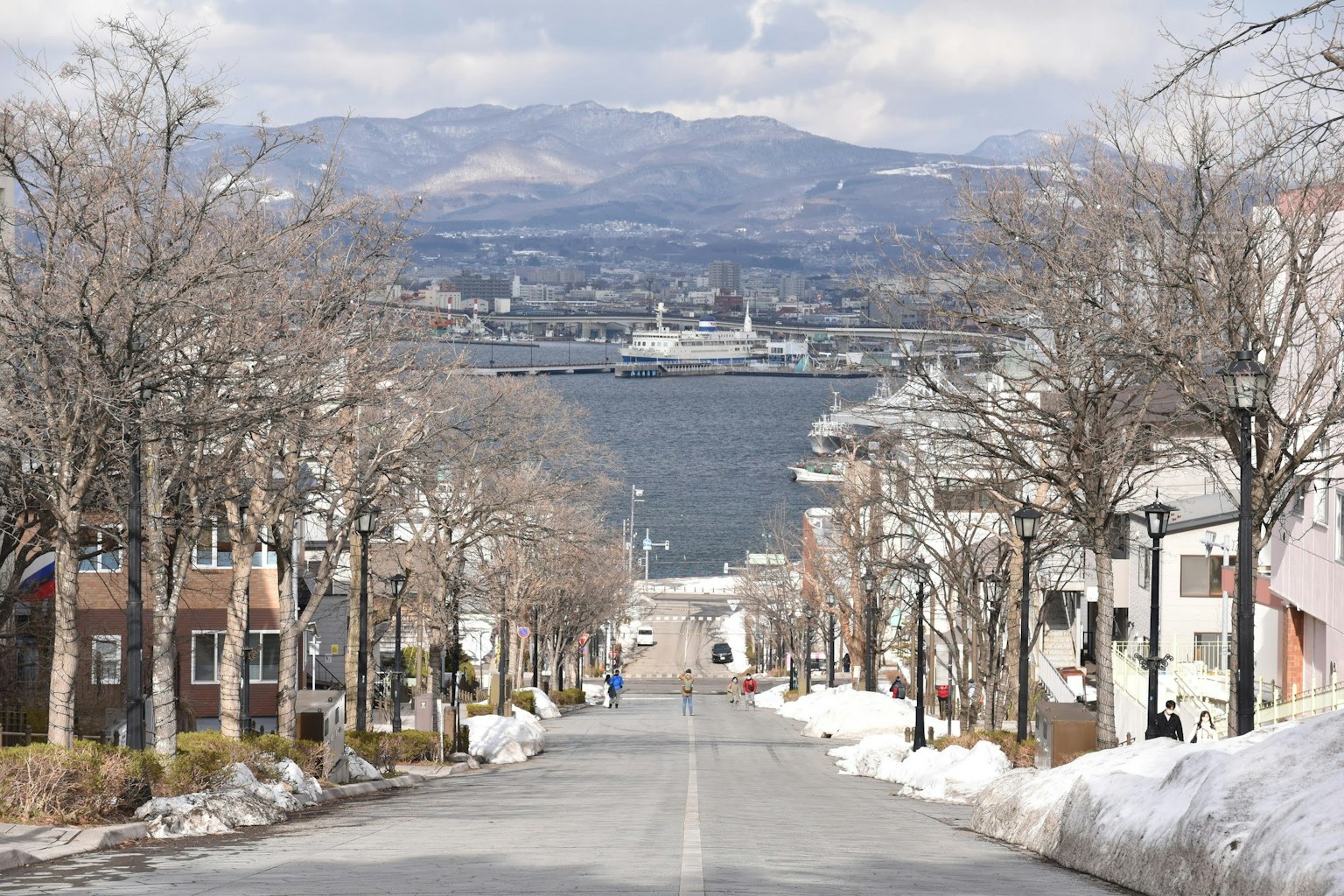 Street view with snow remnants and harbor in the background