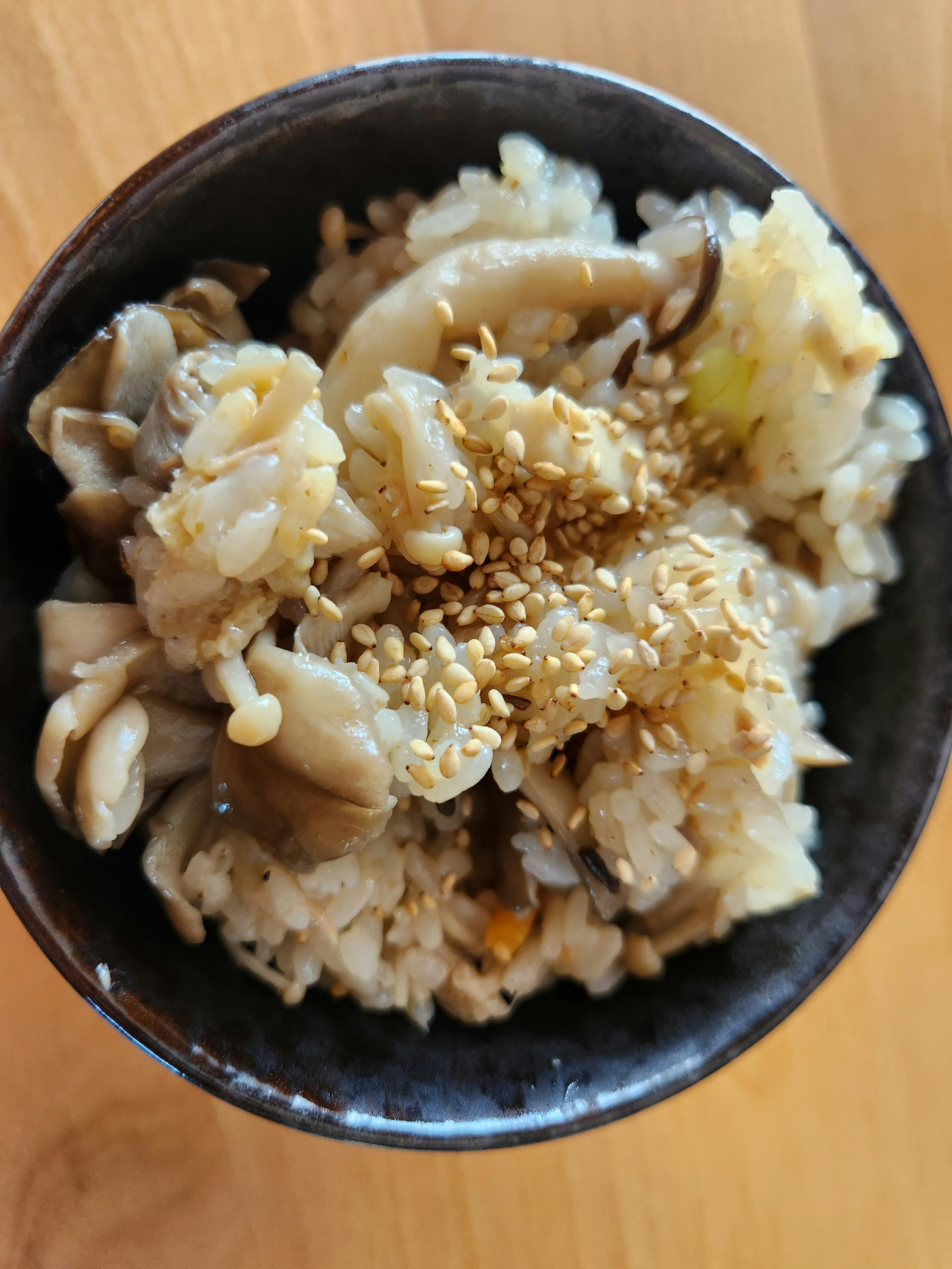 黑色碗装的拌饭，上面撒白芝麻