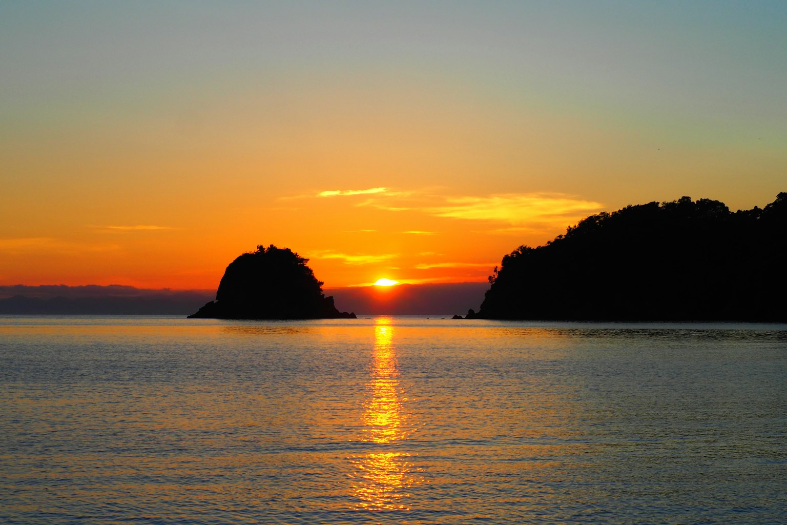 Schöner Sonnenuntergang über ruhigem Wasser mit Silhouetten von Inseln